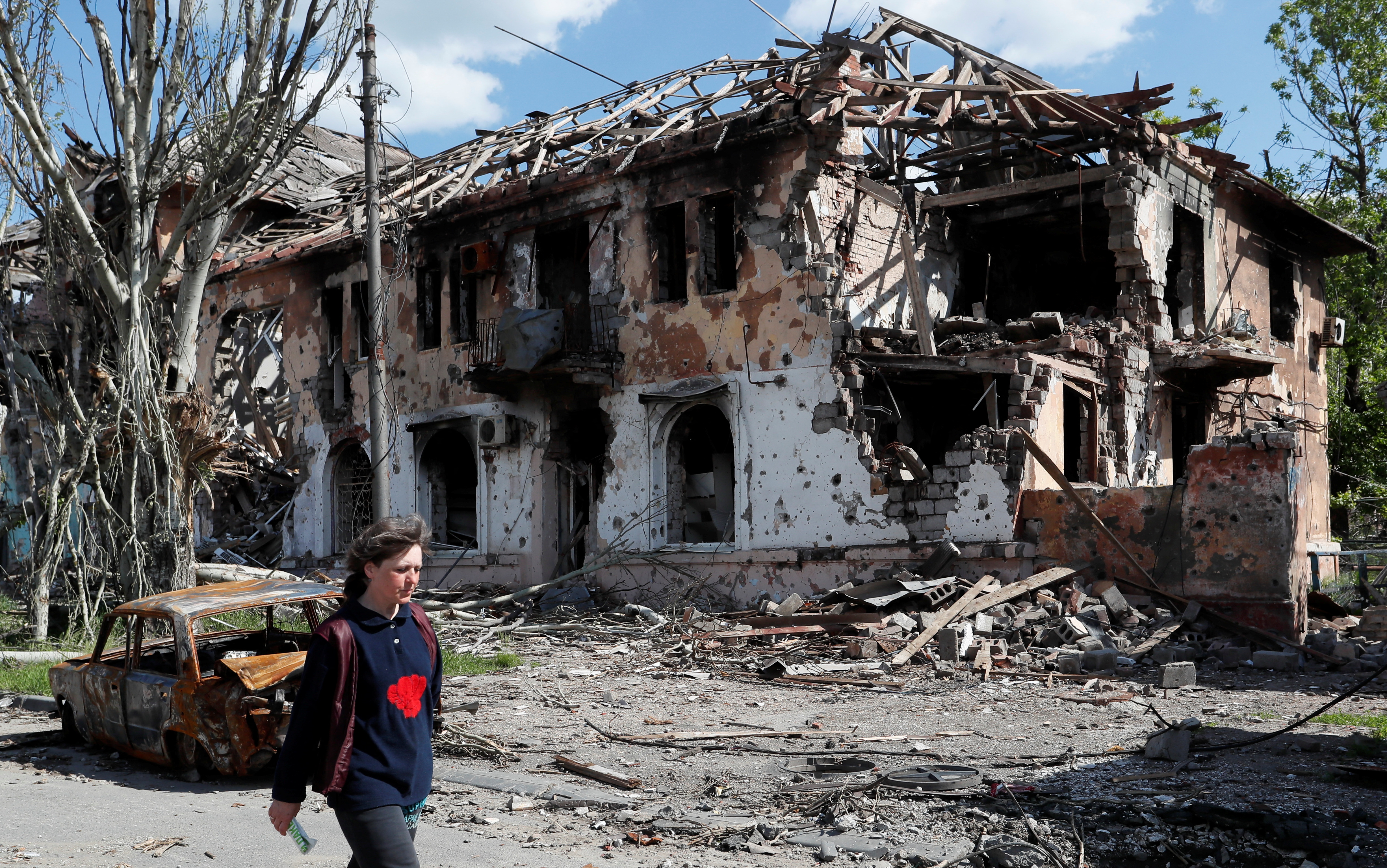 A local resident walks past a heavily damaged building in Mariupol