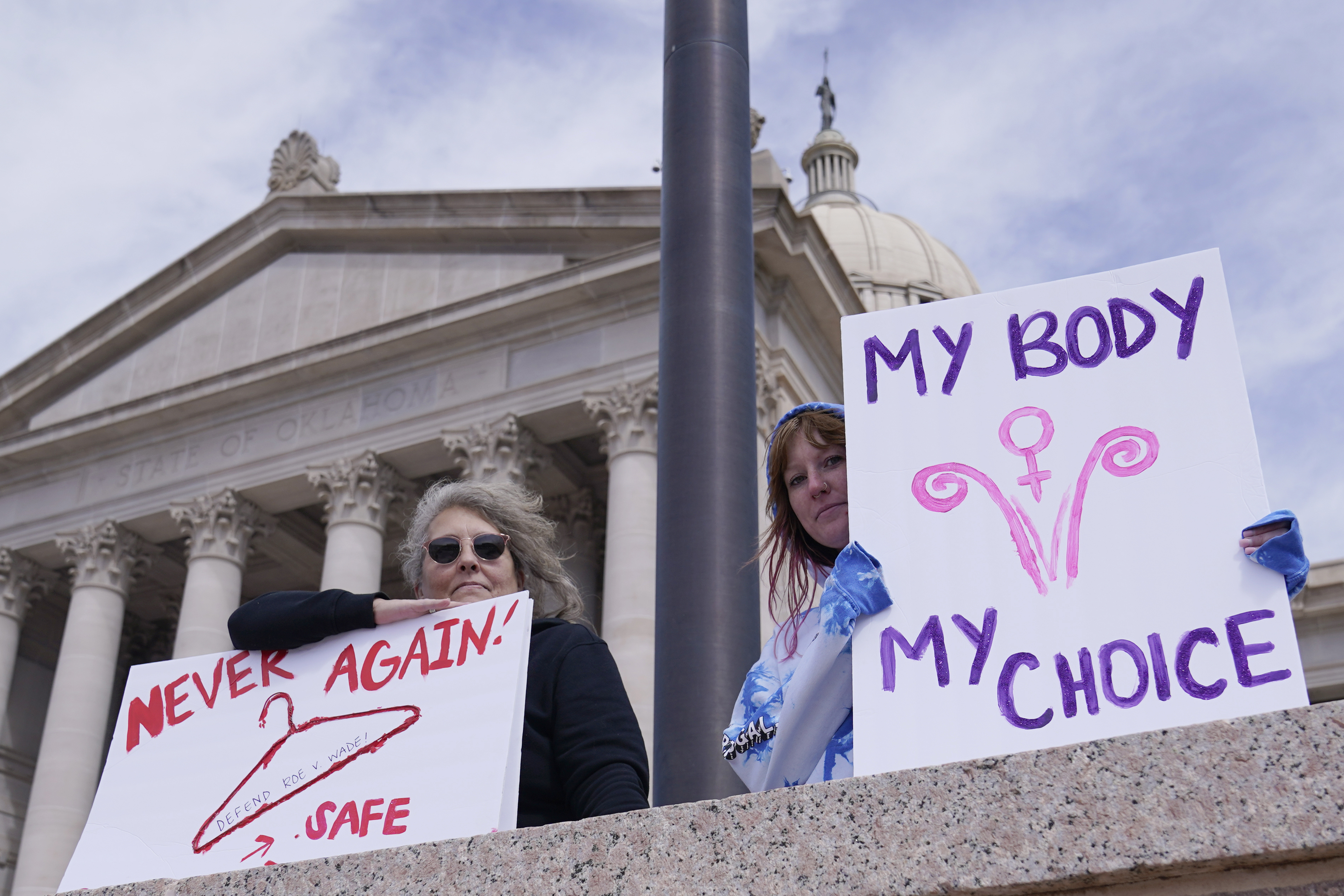 Women protesting in favour of abortion carry placards reading 'My body, my choice' and 'Never again' with a drawing of a coat hanger, which have often been used in backstreet abortions