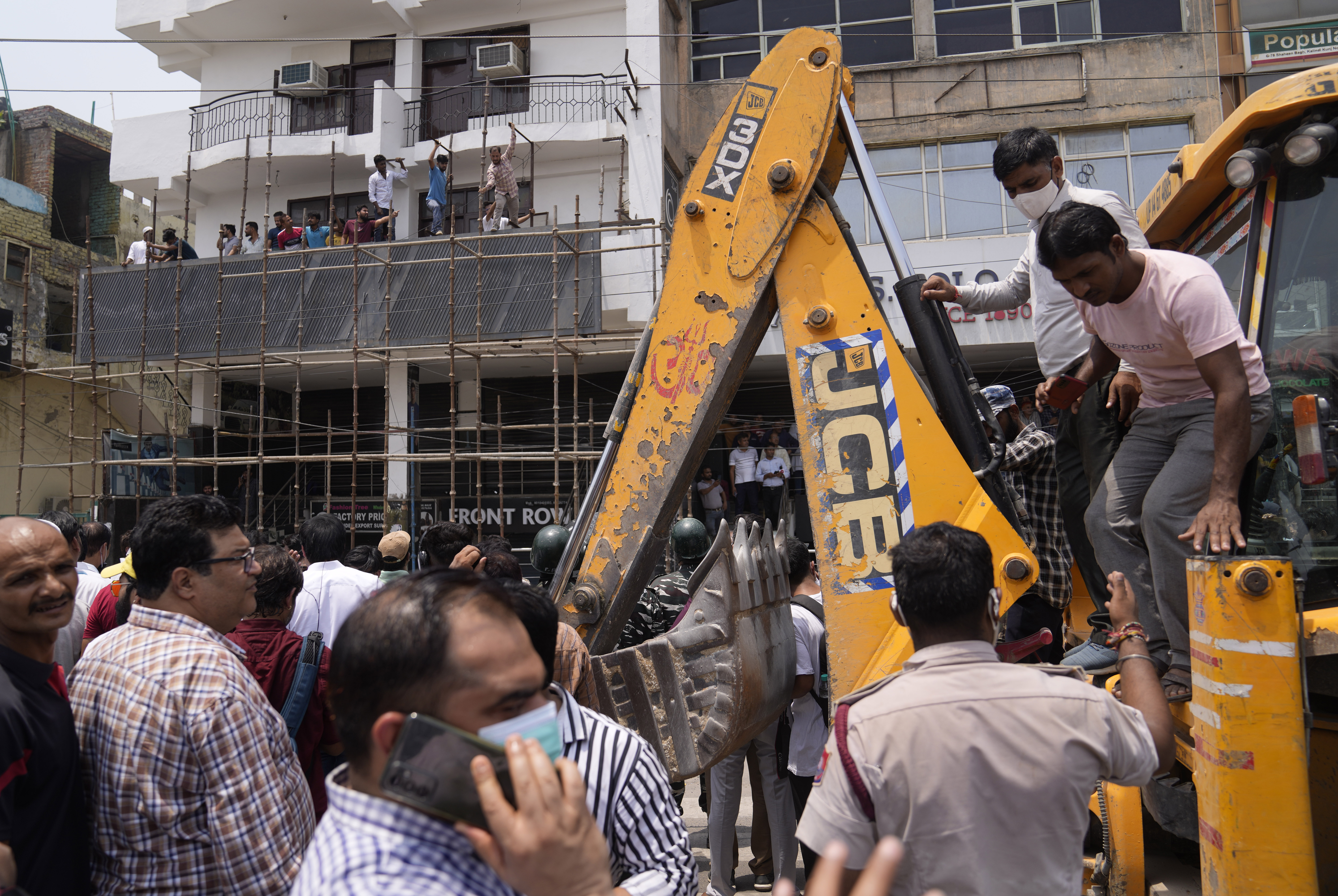 Residents and officials crowd around a bulldozer during a demolition drive in New Delhi