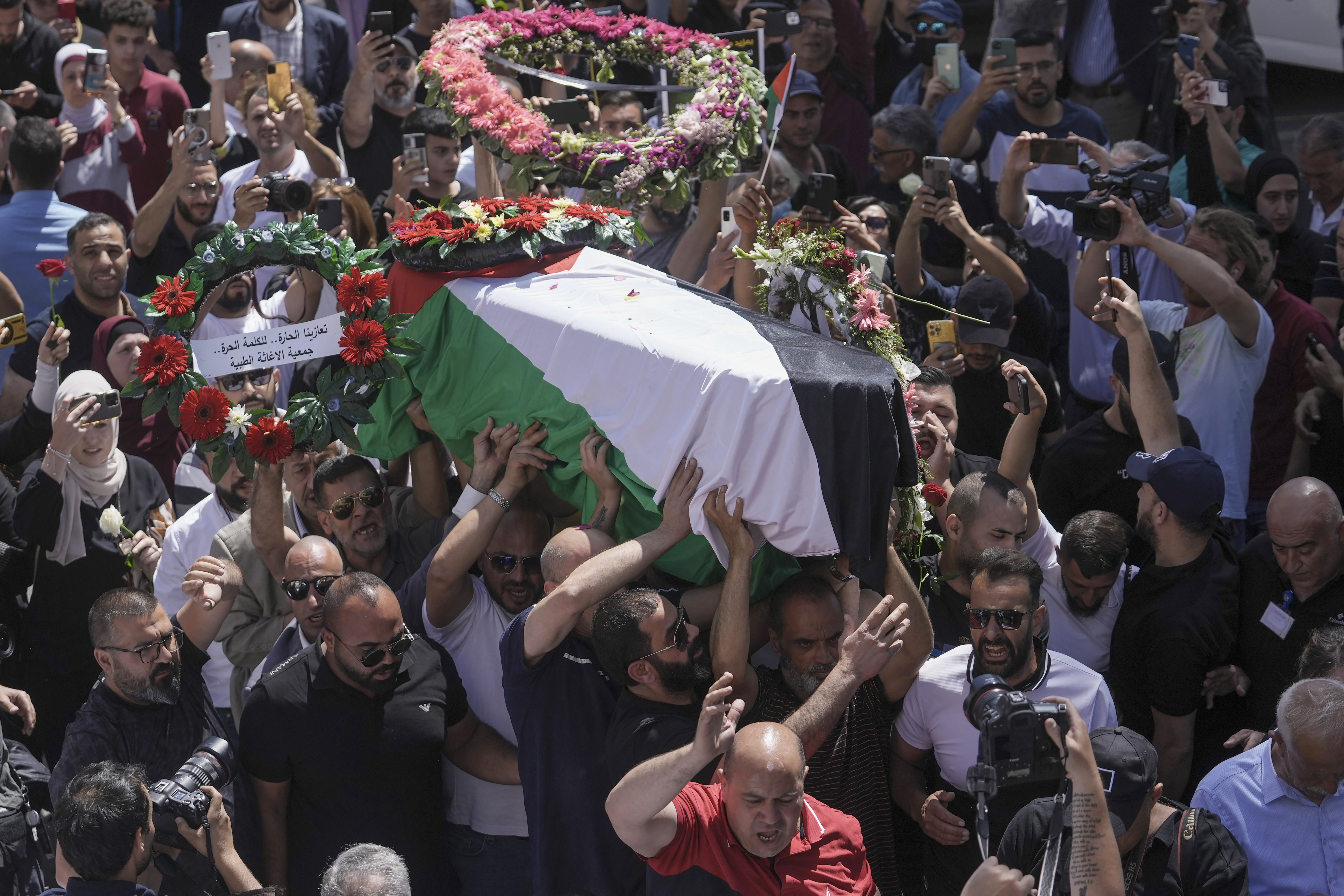Family, friends and colleagues of slain Al Jazeera journalist Shireen Abu Akleh carry her coffin to a hospital