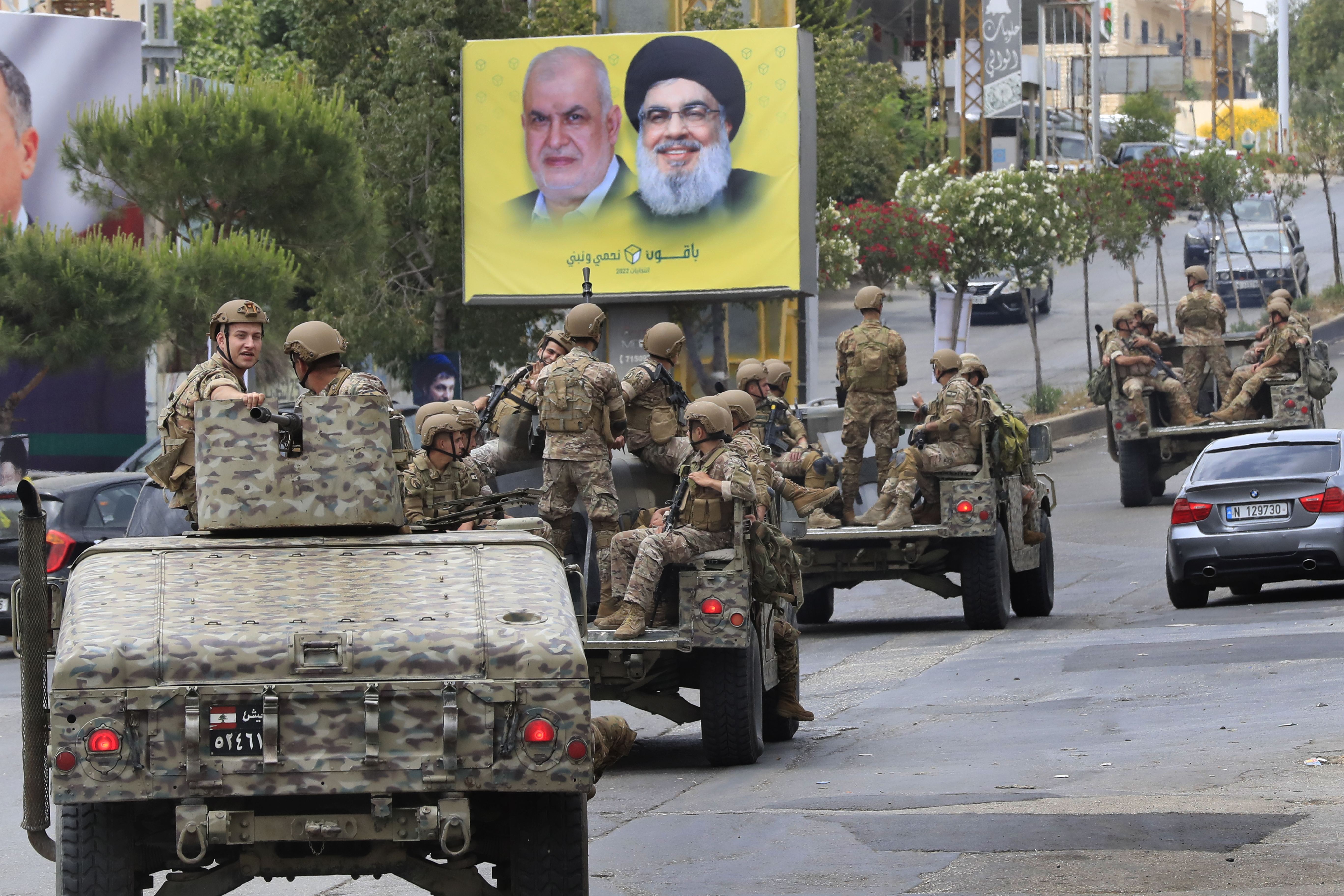 Lebanese army patrol past a poster showing portraits of Hezbollah leader Hassan Nasrallah, right, and the head of Hezbollah's parliamentary bloc, Mohammed Raad, in Nabatiyeh, south Lebanon