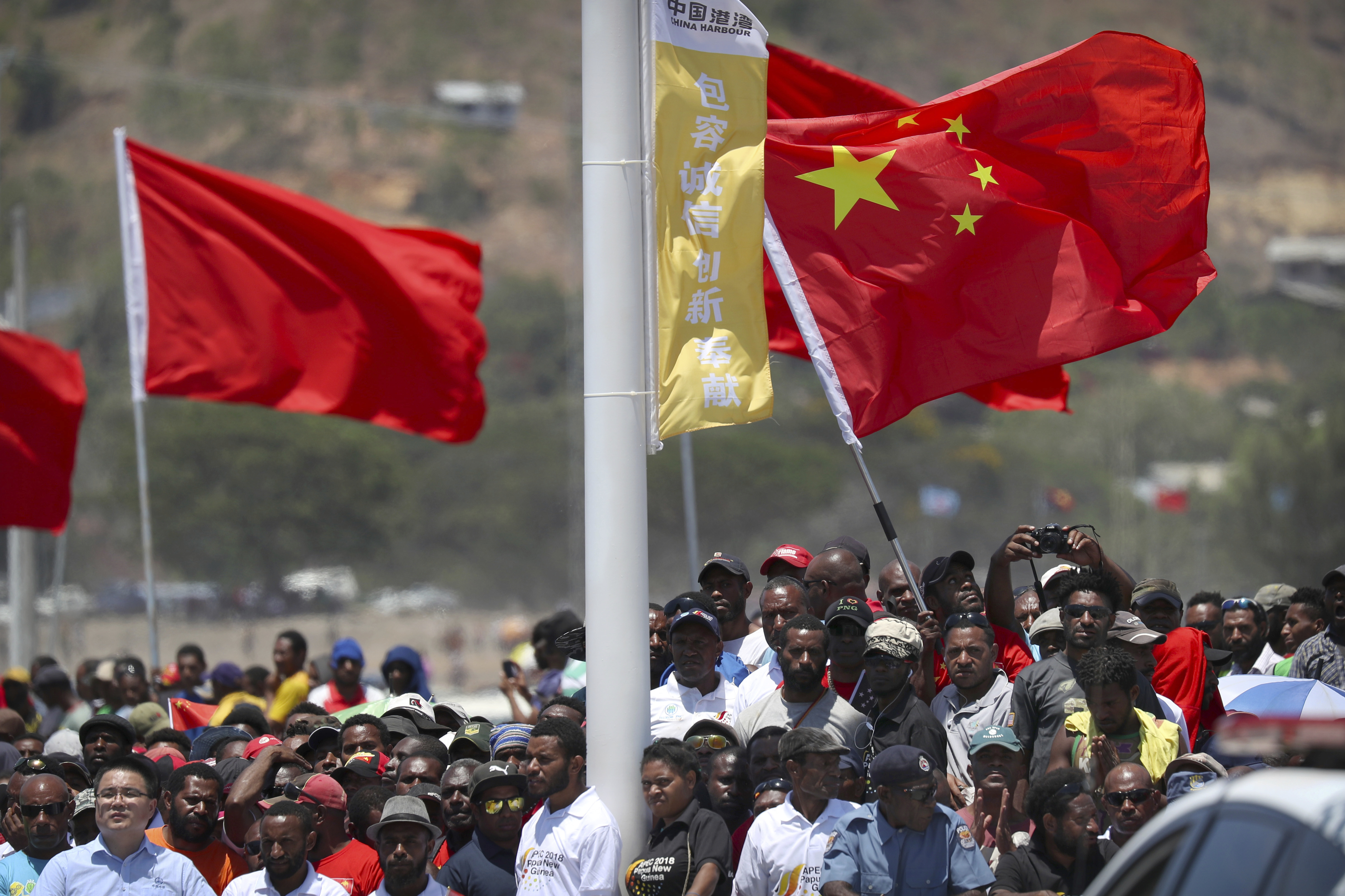 Spectators hold a Chinese flag as they watch a ceremony.