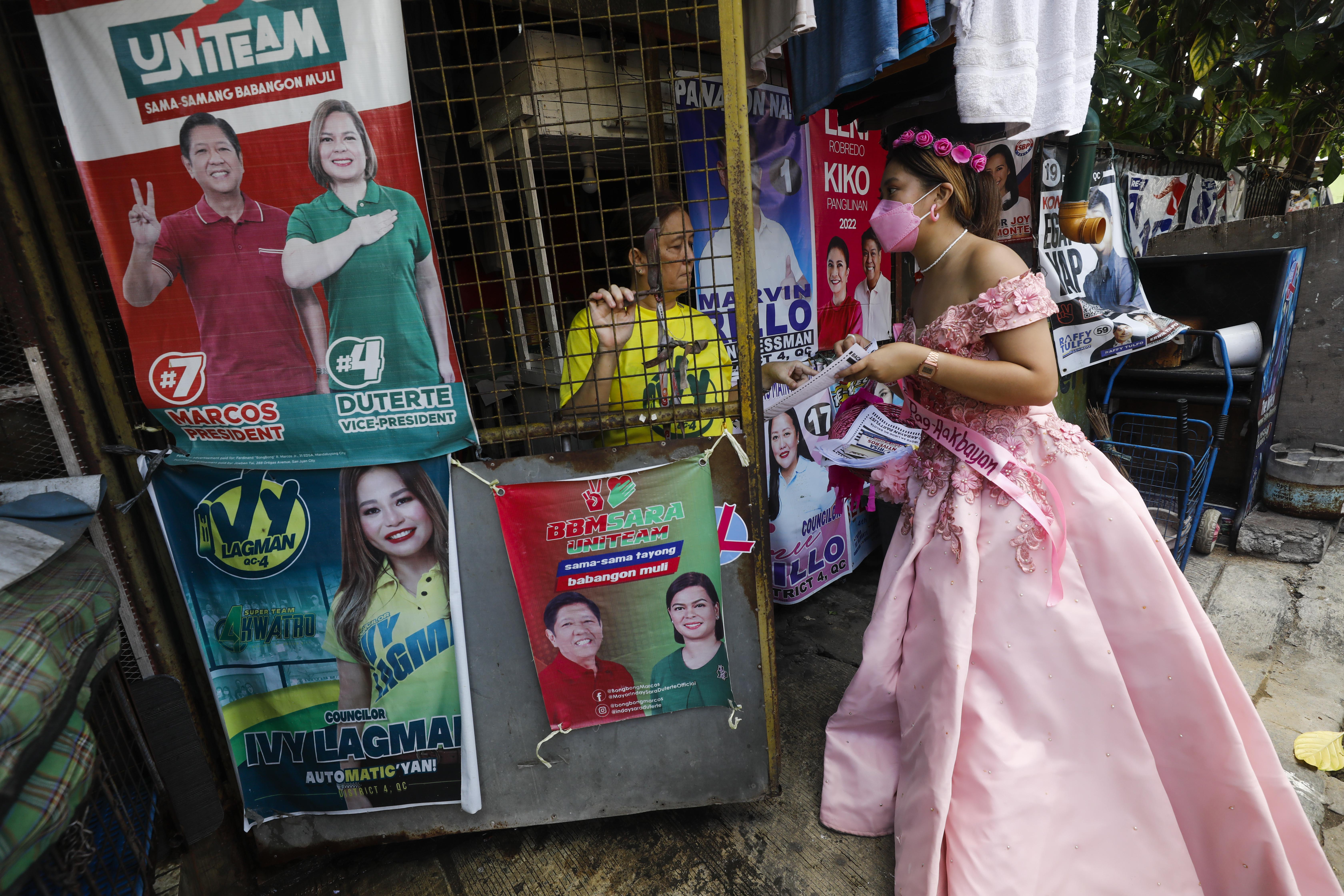 A Robredo supporter dressed in a long pink ball gown for the 'Flowers of May' goes door to door in a Quezon City neighbourhood