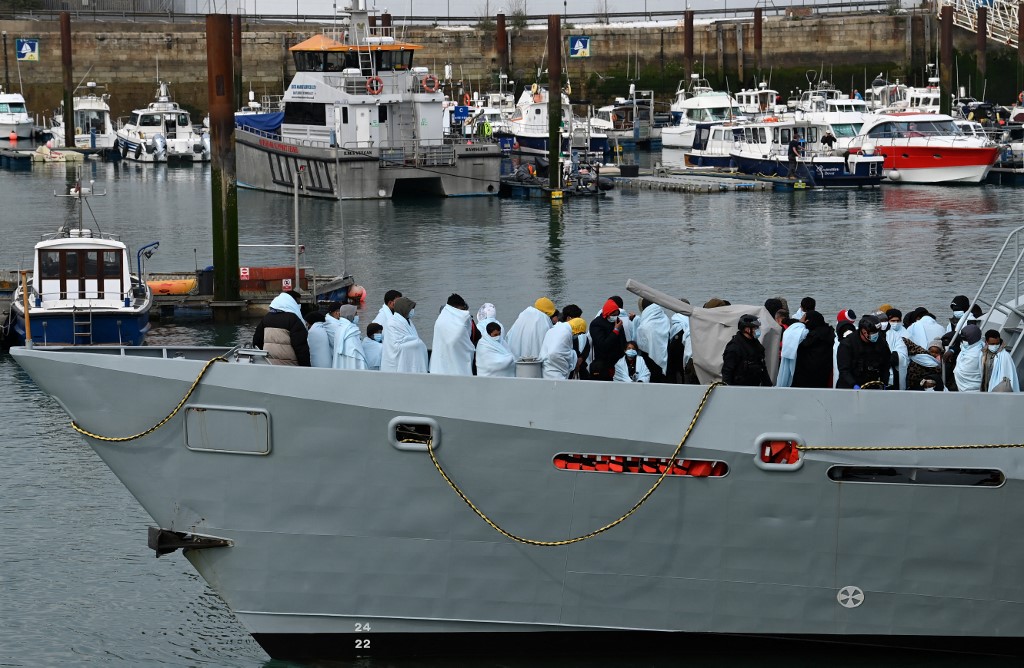 Migrants huddle together under blankets, brought to port by the UK Border Force after being picked up crossing the English Channel from France