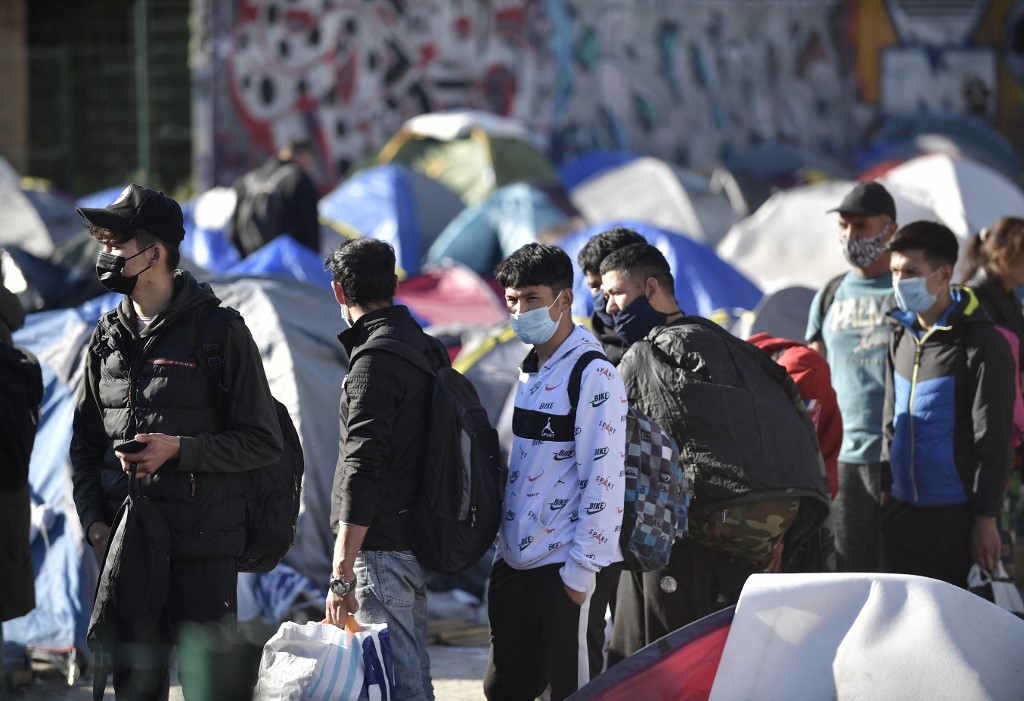 Asylum seekers line up with their belongings next to tents during the evacuation of a camp of migrants, mainly from Afghanistan, by police forces in Pantin, northeastern suburbs of Paris