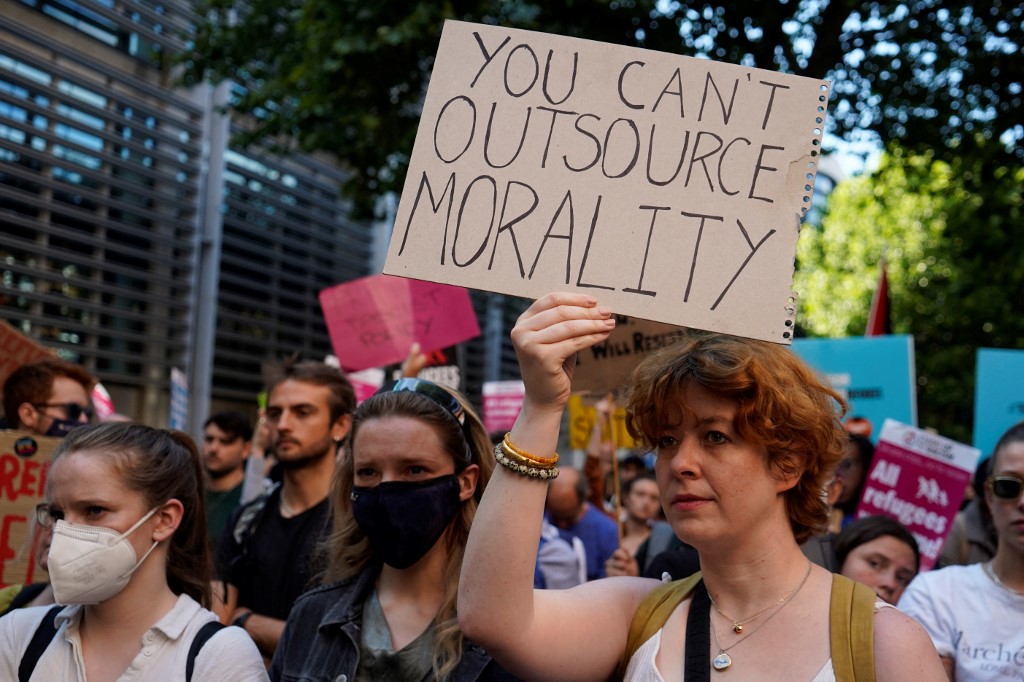 Protesters hold placards as they gather outside the Home Office in central London