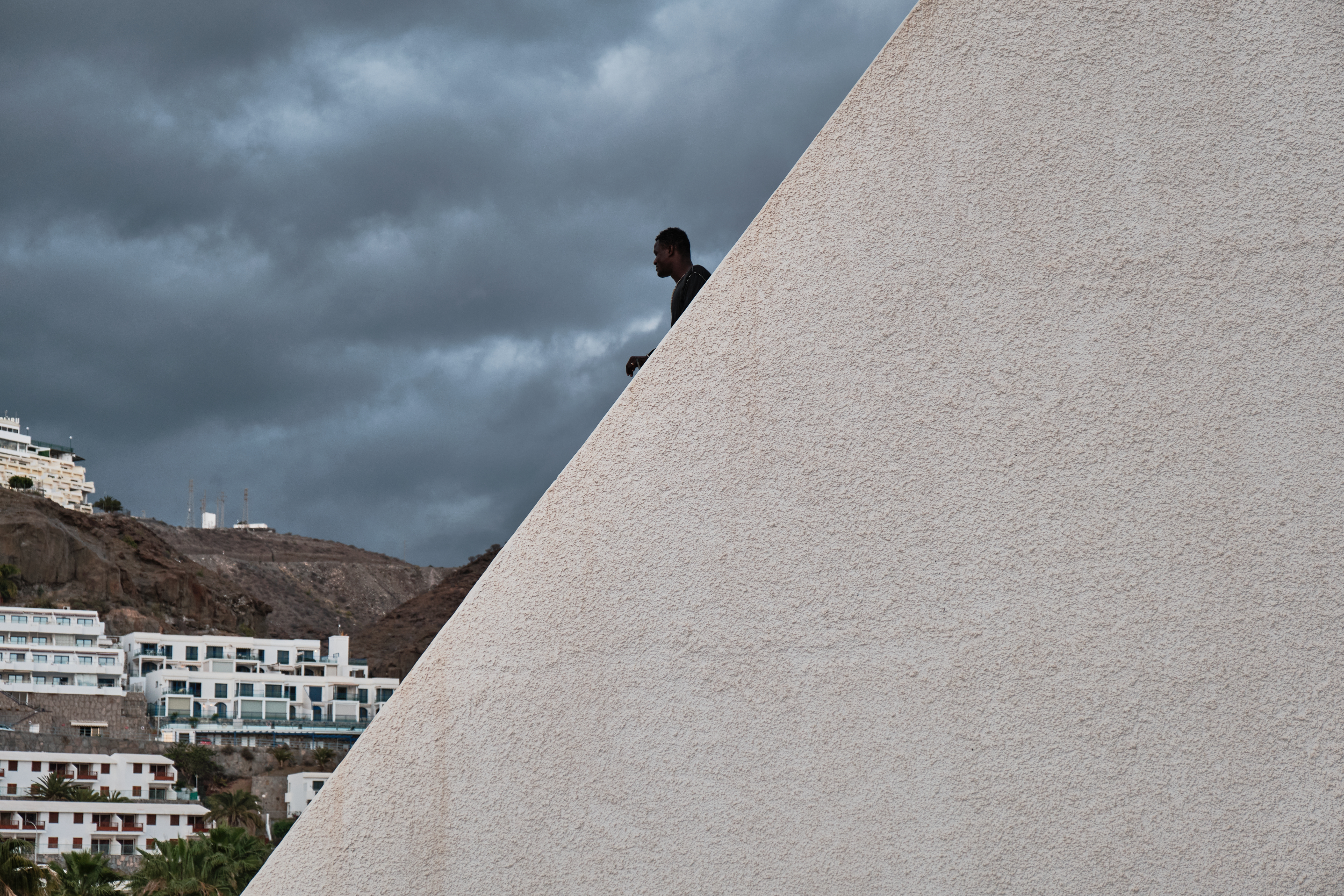 A photo of a young man from Senegal looking out at the horizon from the top of a building.