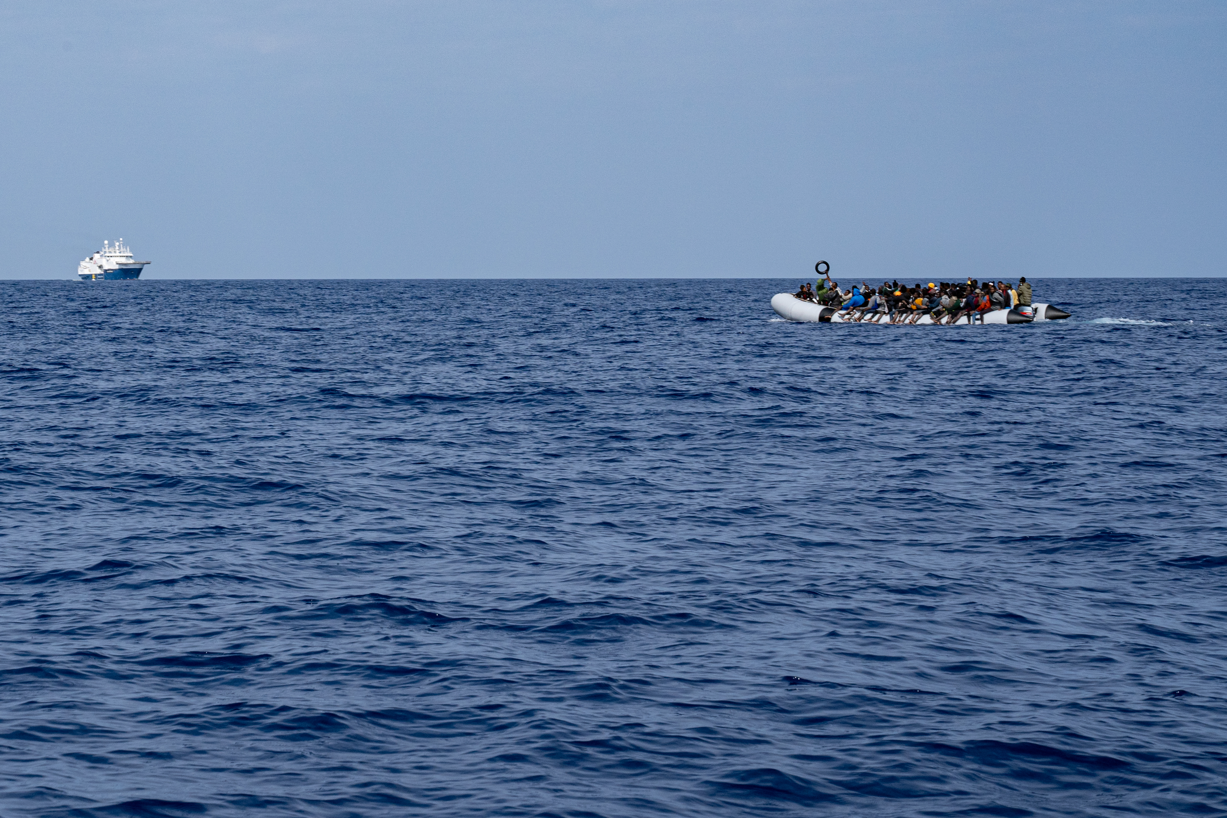 An inflatable boat with over 100 people onboard floats in the Med sea