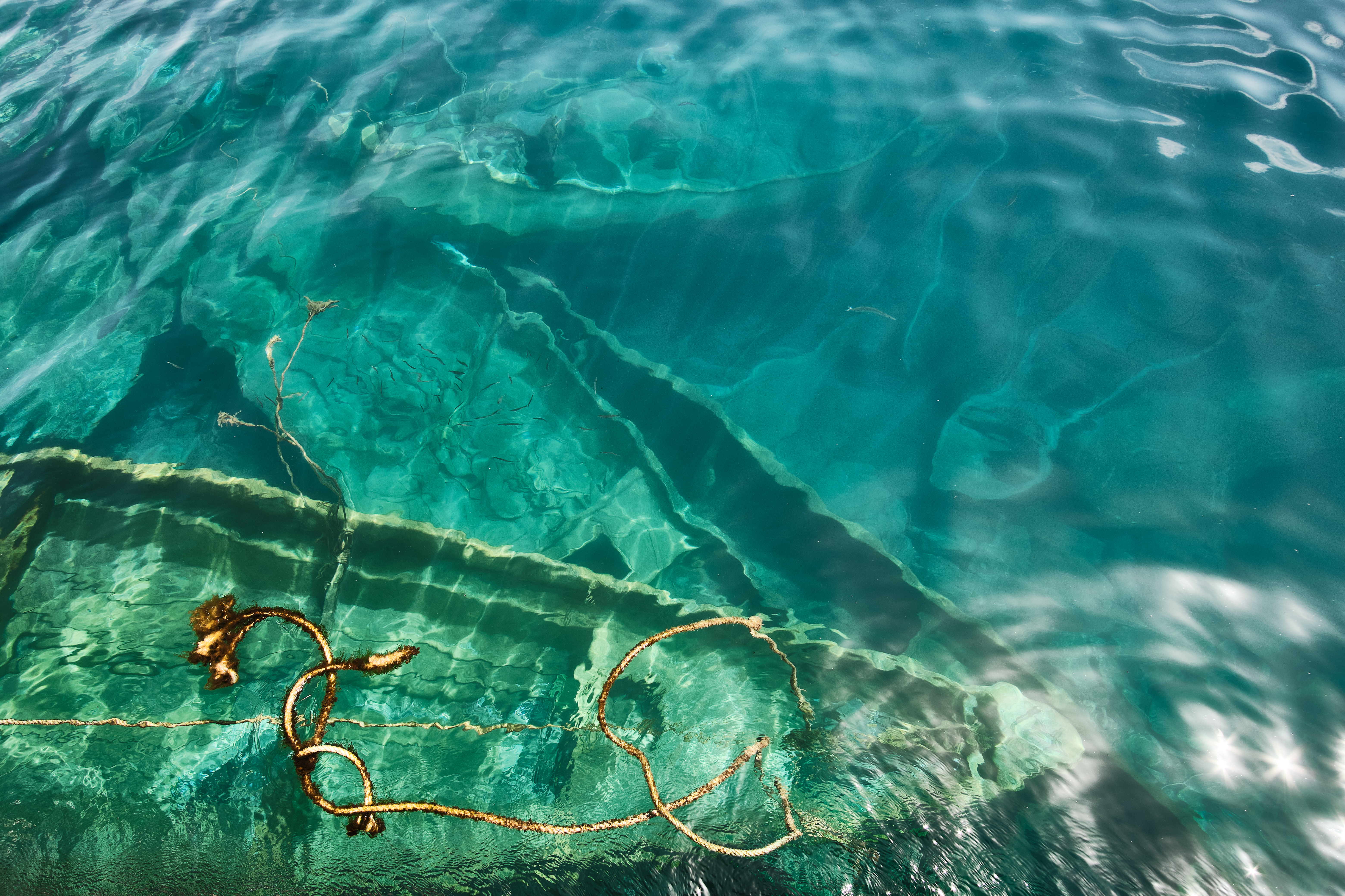 A photo of several boats under the sea that have sunk in the port of Arguineguín, in Gran Canaria.