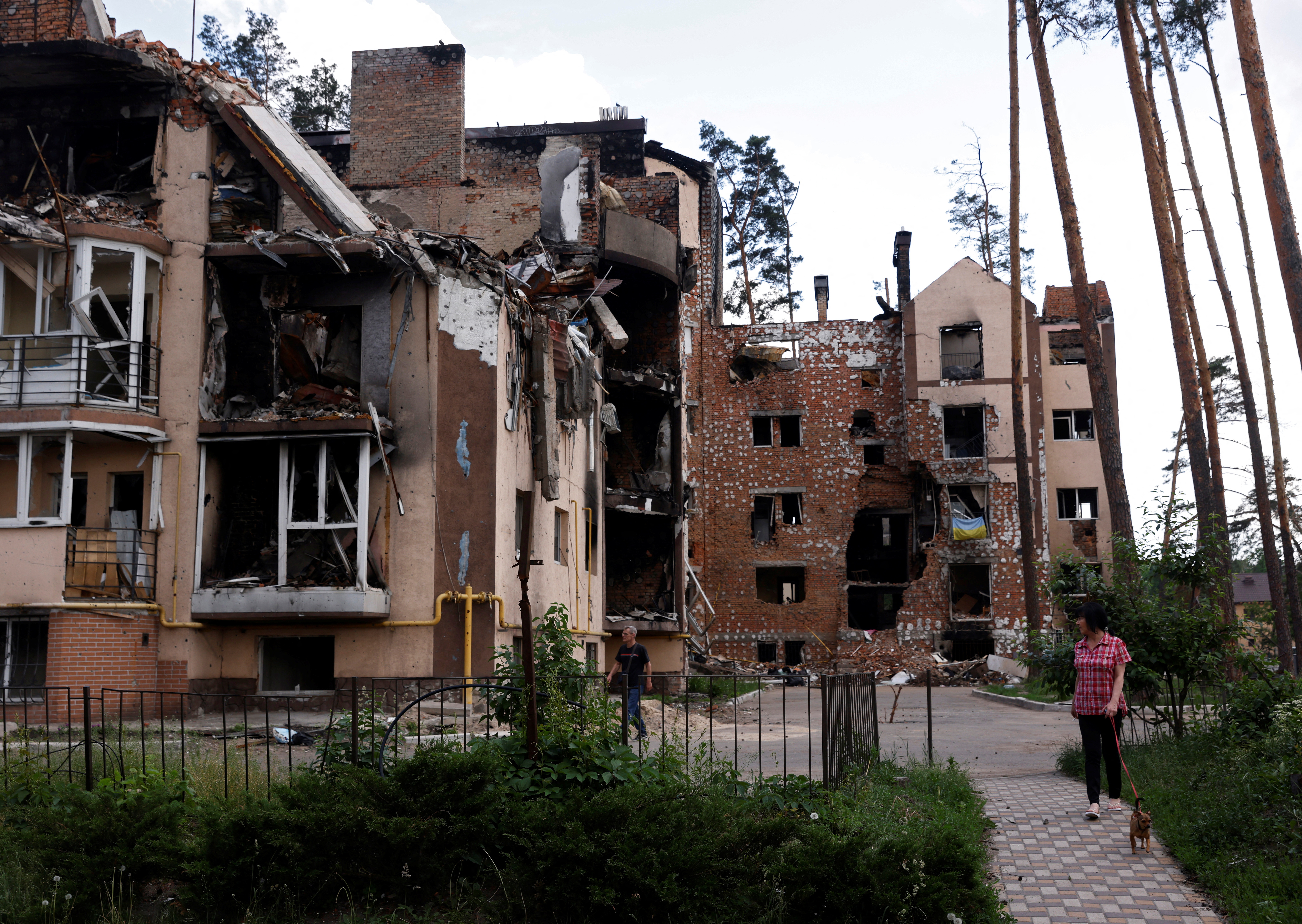 Resident Lyudmila, who lives in a destroyed apartment block, walks her dog near her home in Irpin, outside Kyiv, as Russia's attacks on Ukraine continues