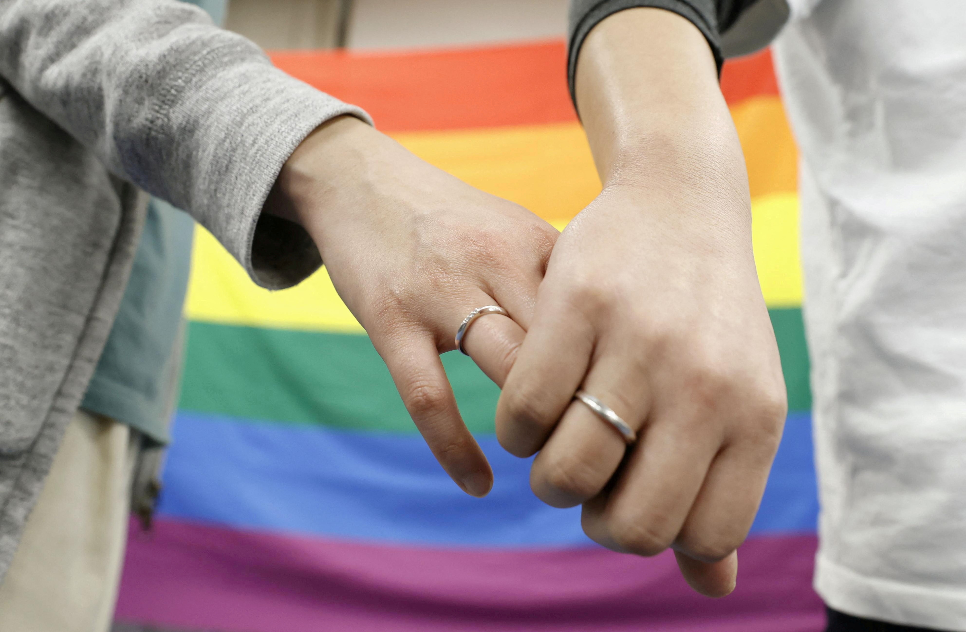 Plaintiffs hold hands each other after a district court ruled on the legality of same-sex marriages outside Sapporo district court in Sapporo, Hokkaido