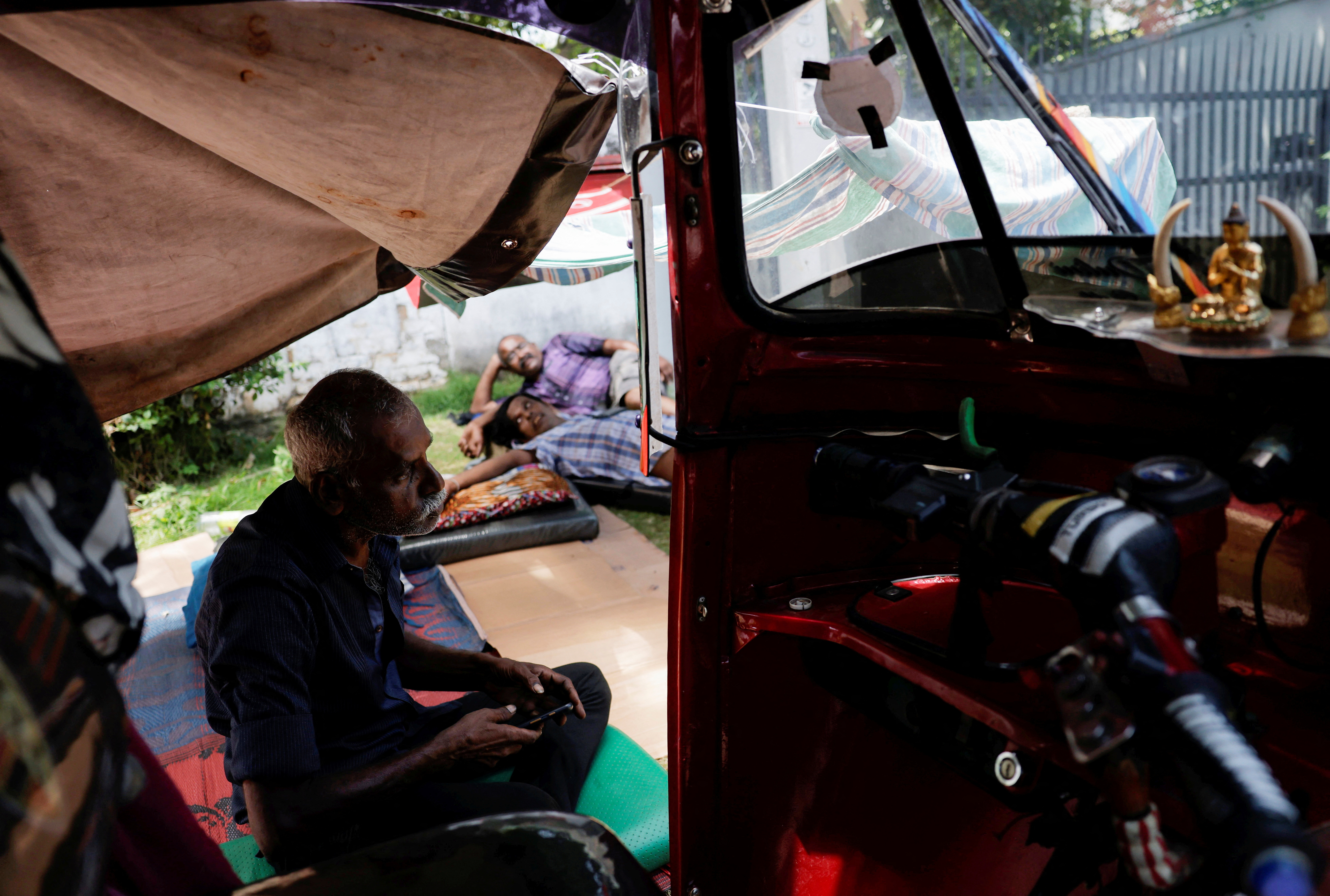People wait under a temporary tent in a queue