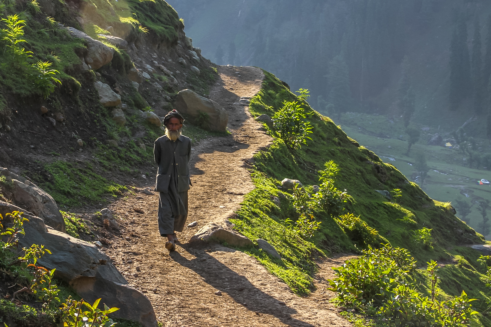 An older gentleman from the village walking down a path cut into the side of the mountain