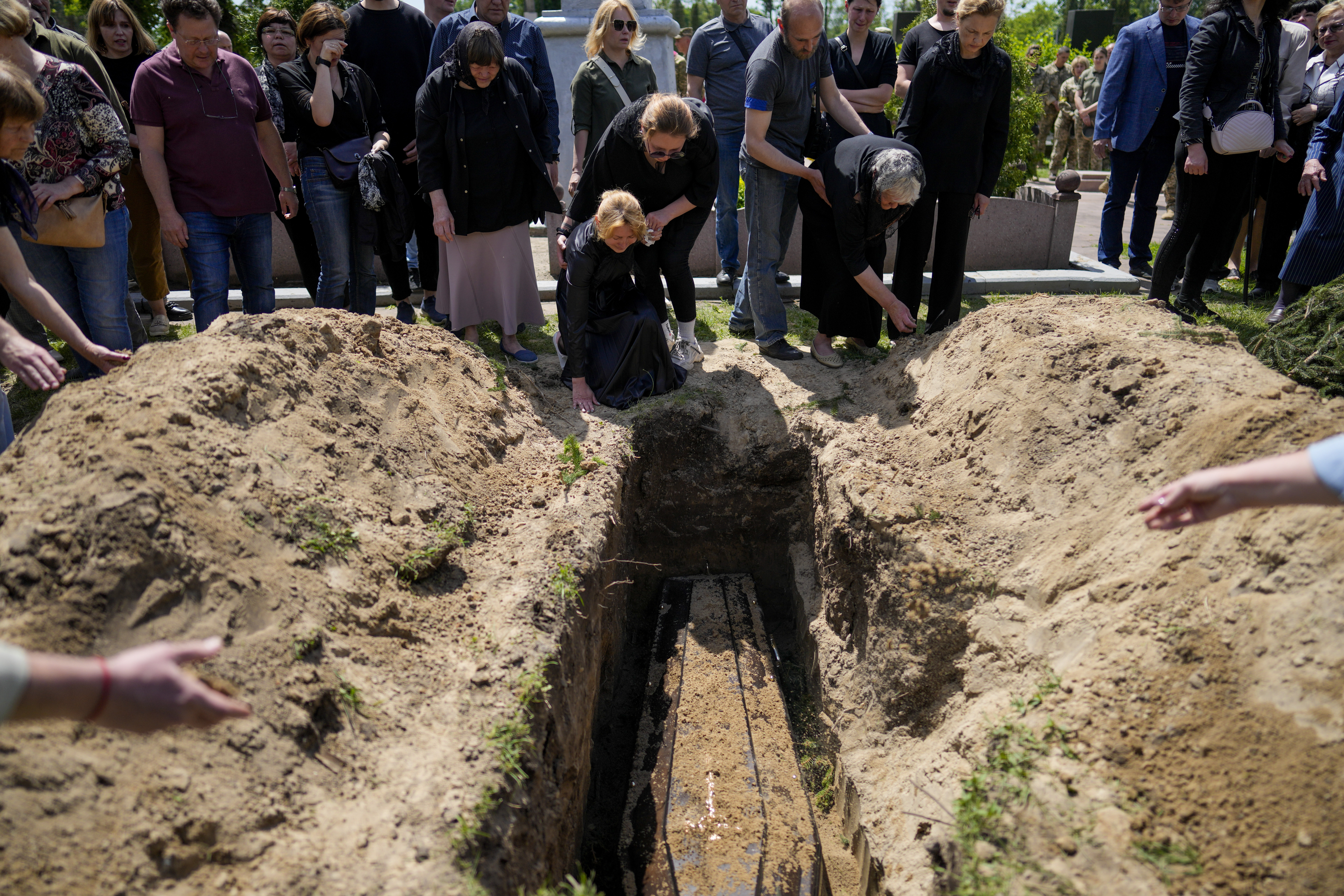 Relatives of Army Col. Oleksander Makhachek mourn during his funeral in Zhytomyr, Ukraine, Friday, June 3, 2022.