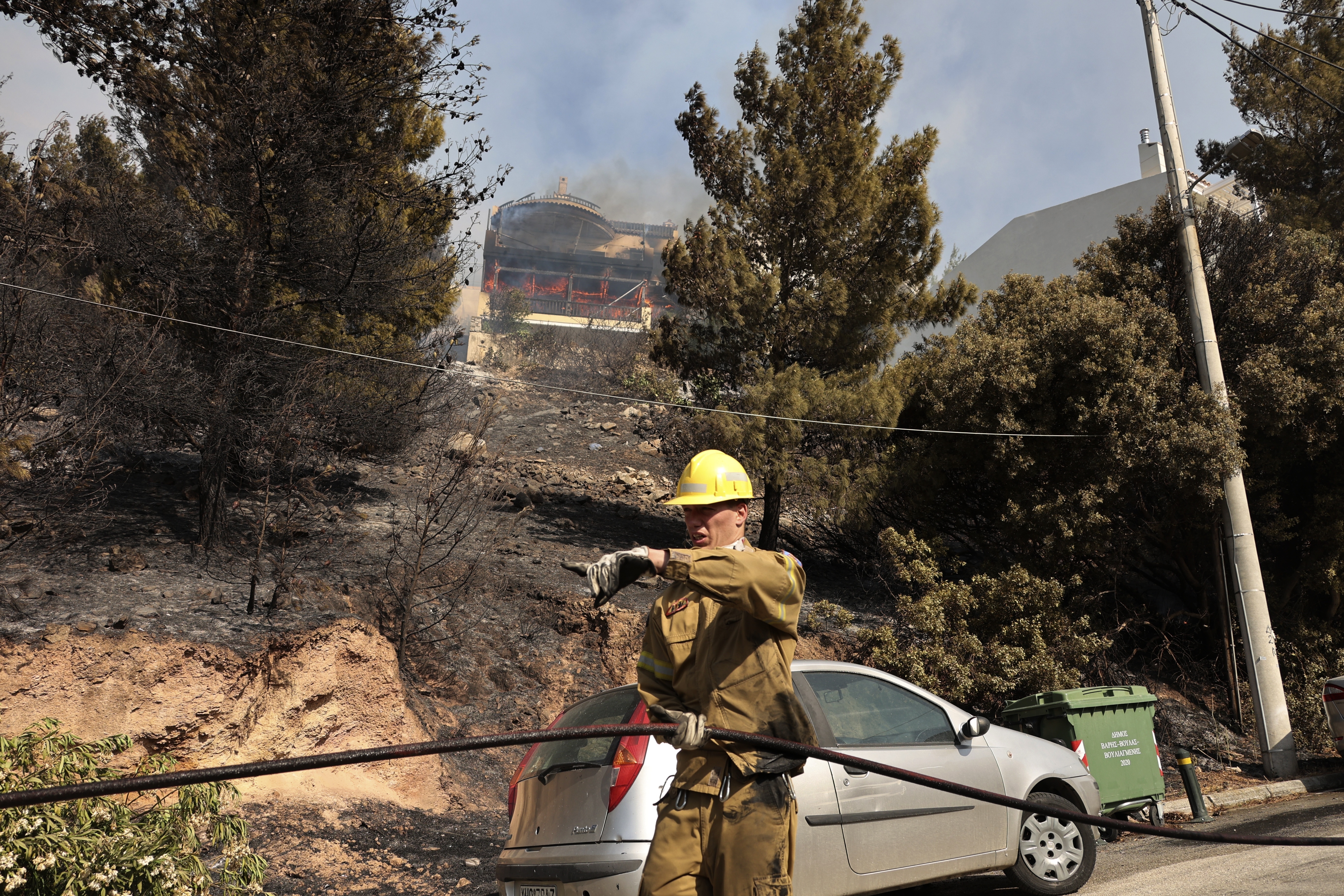 Flames engulf an house as a volunteer firefighter operates during a wildfire in Voula suburb, in southern Athens, Greece, Saturday, June 4, 2022 [Yorgos Karahalis/AP]