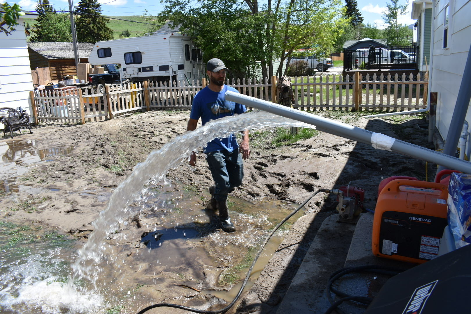 Micah Hoffman is seen in his mud-covered yard as a pump removes water from his basement