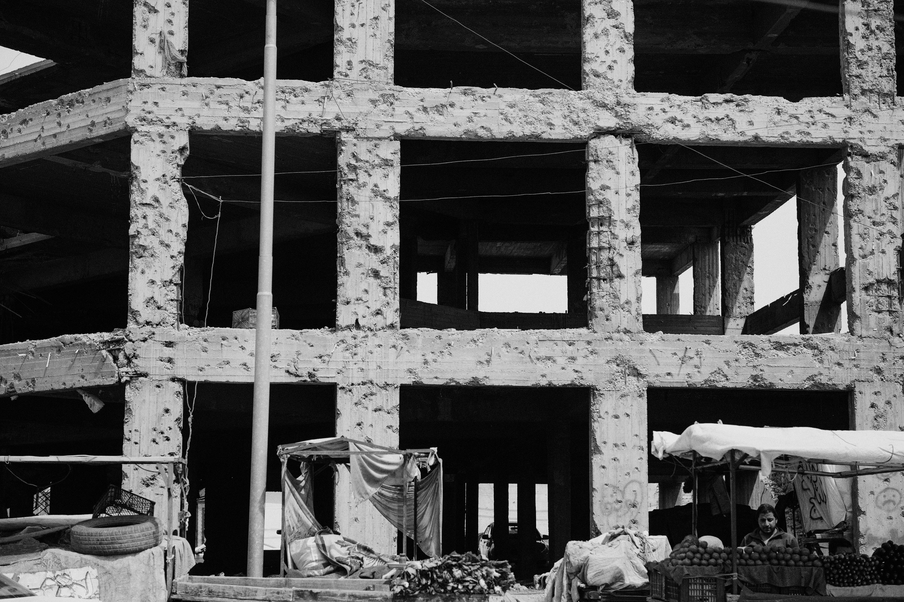 Iraq, Mosul. A street vendor set up his business in front of a building that still shows the signs of the violent clashes in the city of Mosul.