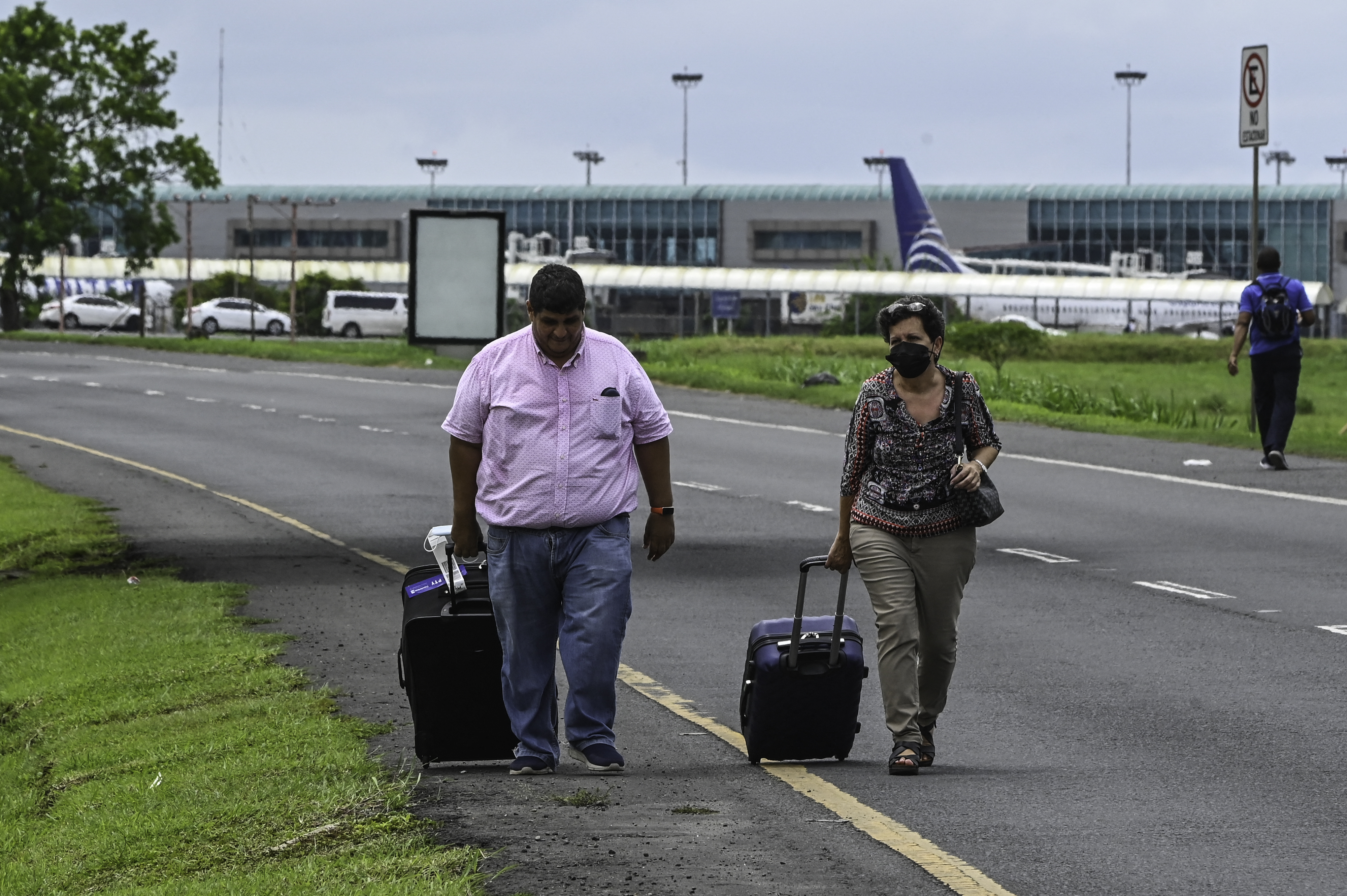 Passengers walk as union workers block the entrance to the Tocumen International airport, in Panama City, on July 18, 2022. - Panama's government and indigenous leaders reached a second deal Sunday to clear all remaining demonstrators from the Panamerican Highway in exchange for lower fuel prices, ending a two-week blockade that had stymied food deliveries. (Photo by Luis ACOSTA / AFP)