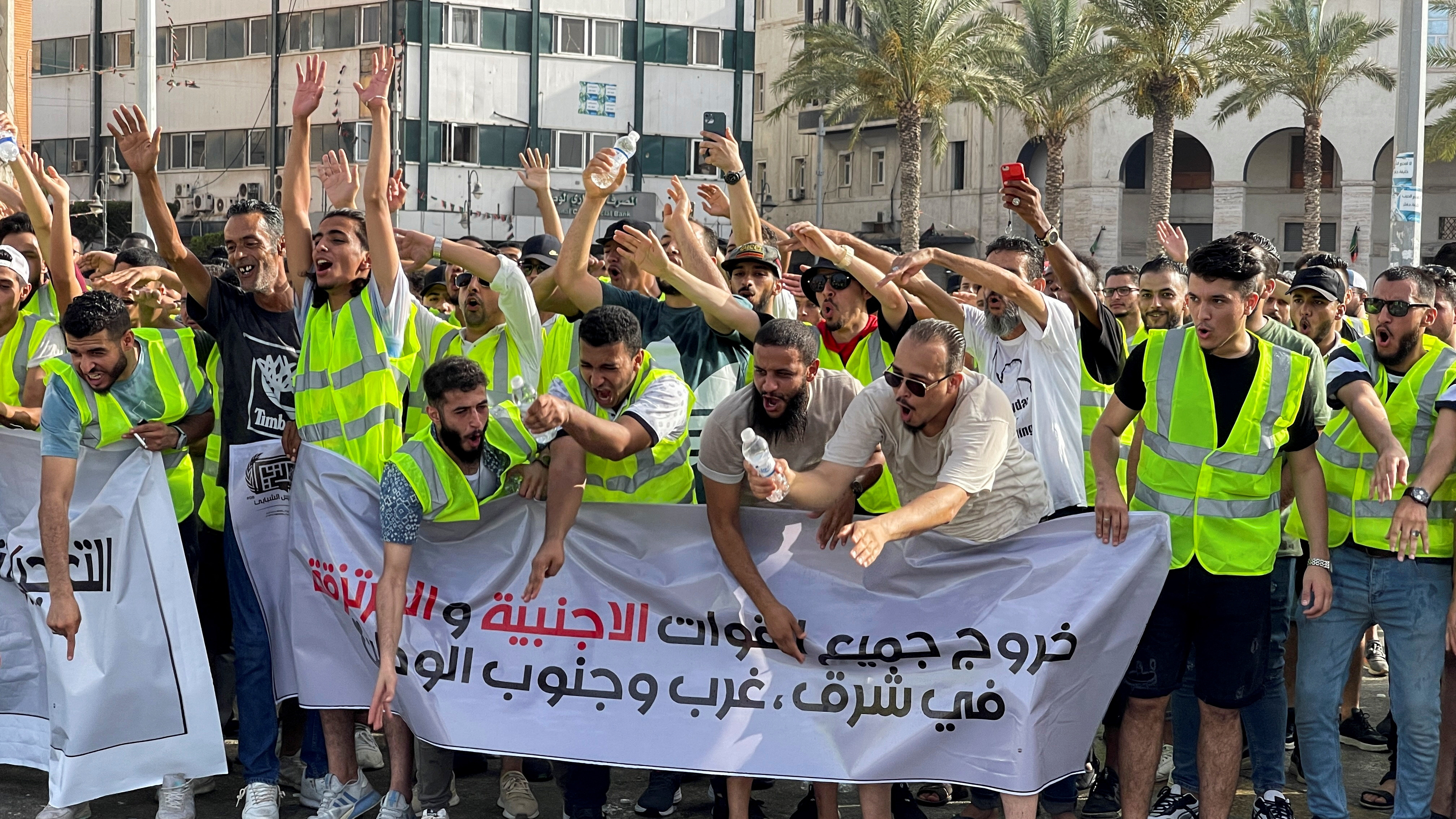 People hold a banner that reads "The exit of all foreign forces in the east and west of the country