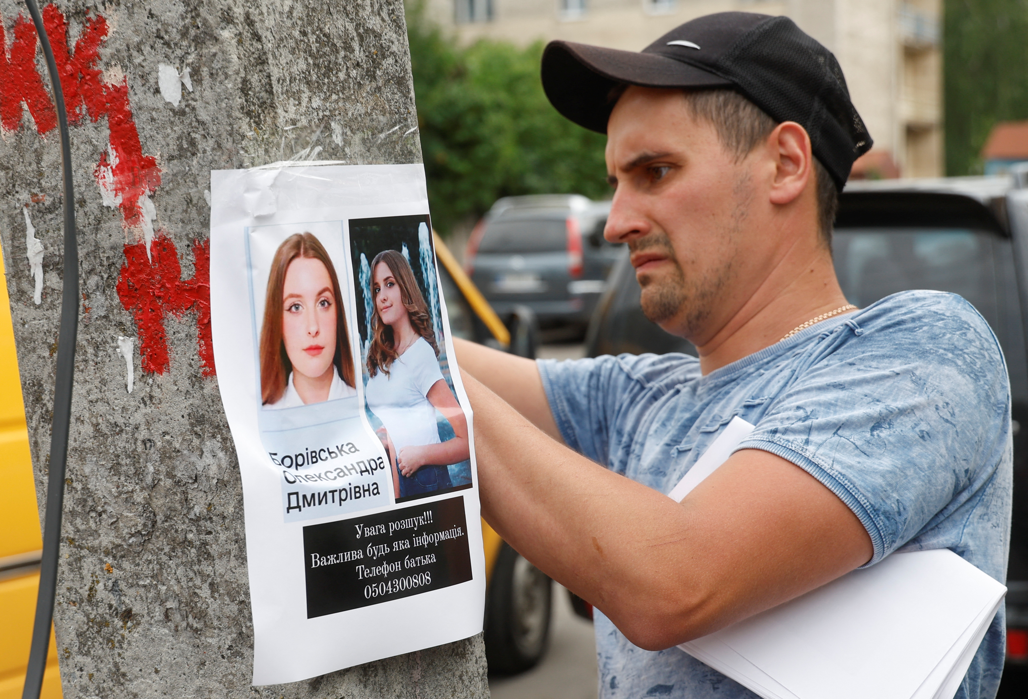 A man places a missing person poster at the site of a Russian missile strike in Vinnytsia, Ukraine on July 15, 2022 [Valentyn Ogirenko/Reuters]