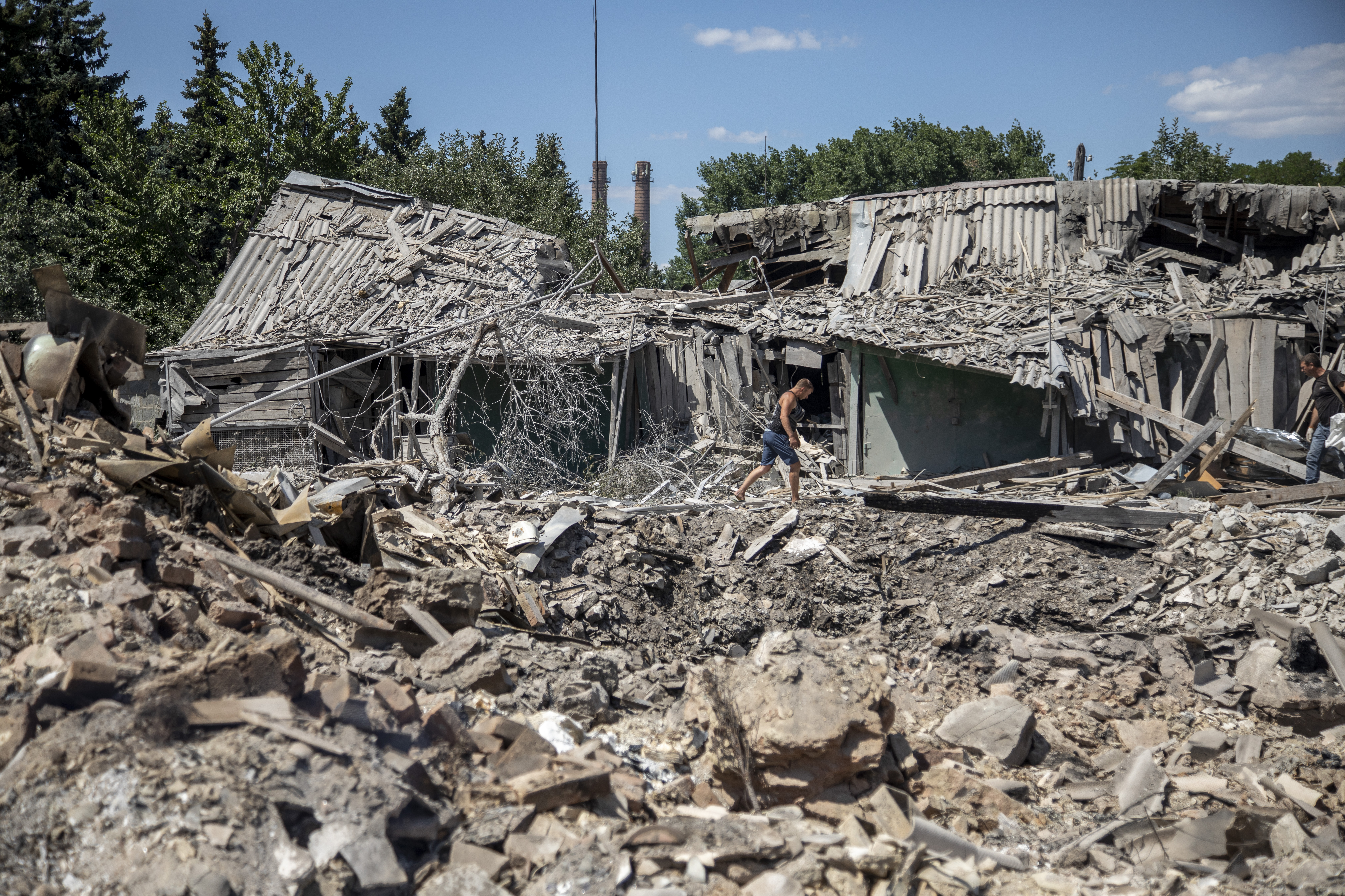 Civilians collect their personal belongings from the rubble after their house was targeted 