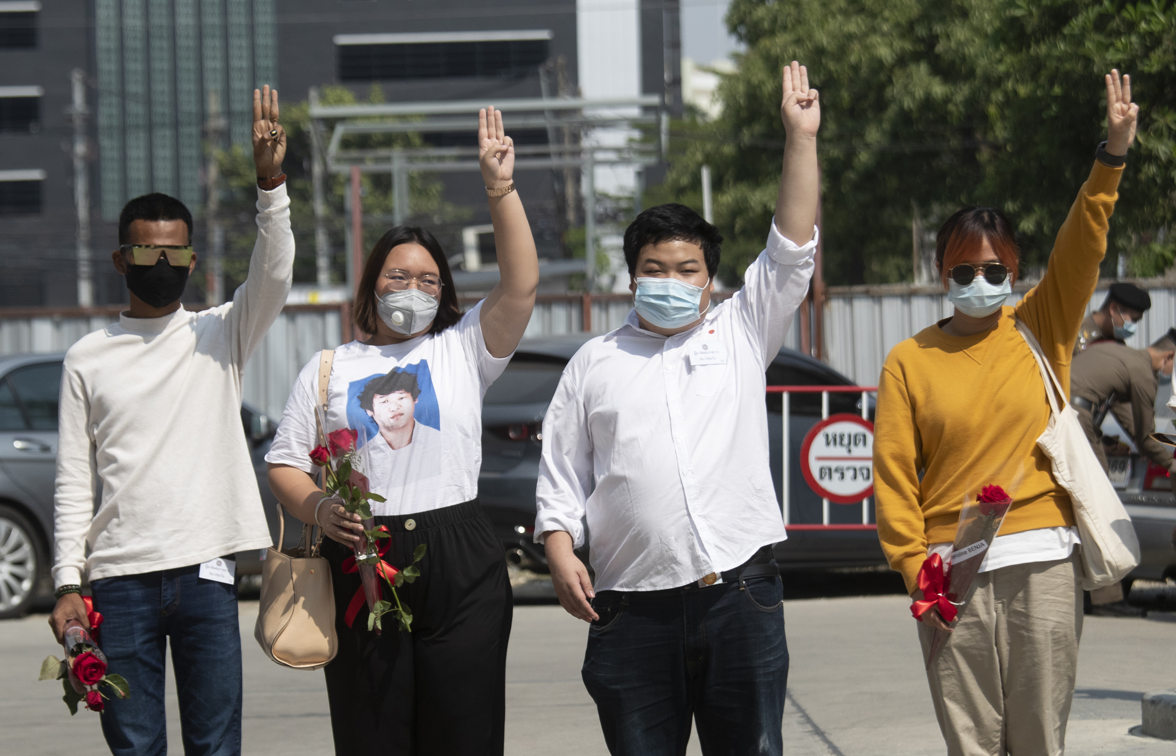 Pro-democracy activists, from left, Panupong Jadnok, Panusaya Sithijirawattanakul, Parit Chiwarak, and Benja Apan, gesture with a three-fingers salute, a symbol of resistance as they walk to Pathumwan police station in Bangkok, Thailand, Wednesday, Jan. 20, 2021. Six pro-democracy activists, including two 17-year old minors, report to police after being issued summonses to answer charges of lese majeste or defaming or insulting key members of the royal family. (AP Photo/Sakchai Lalit)