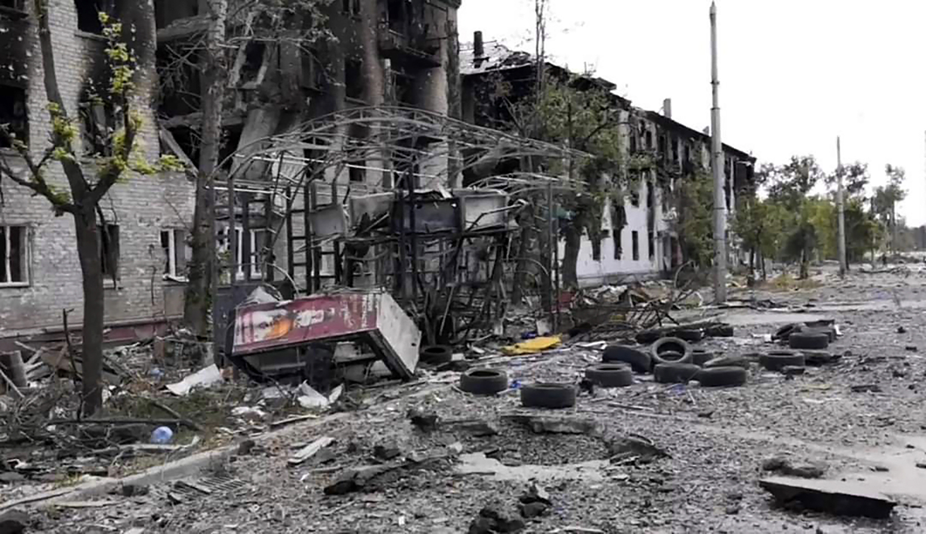 Damaged residential buildings with debris scattered on the roadway in Lysychansk, Ukraine.