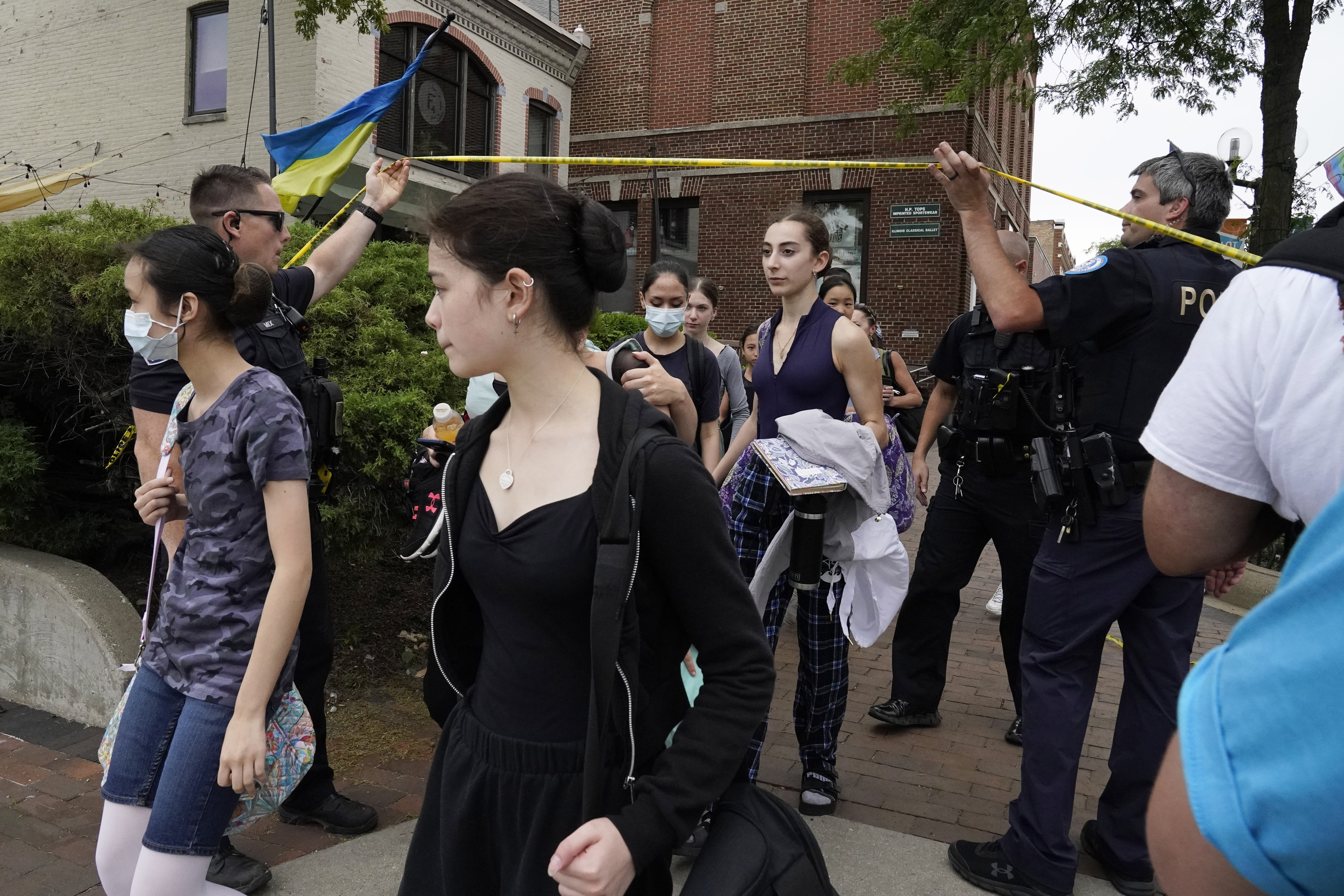 Students are escorted by police officers as they cross under police tape after a mass shooting