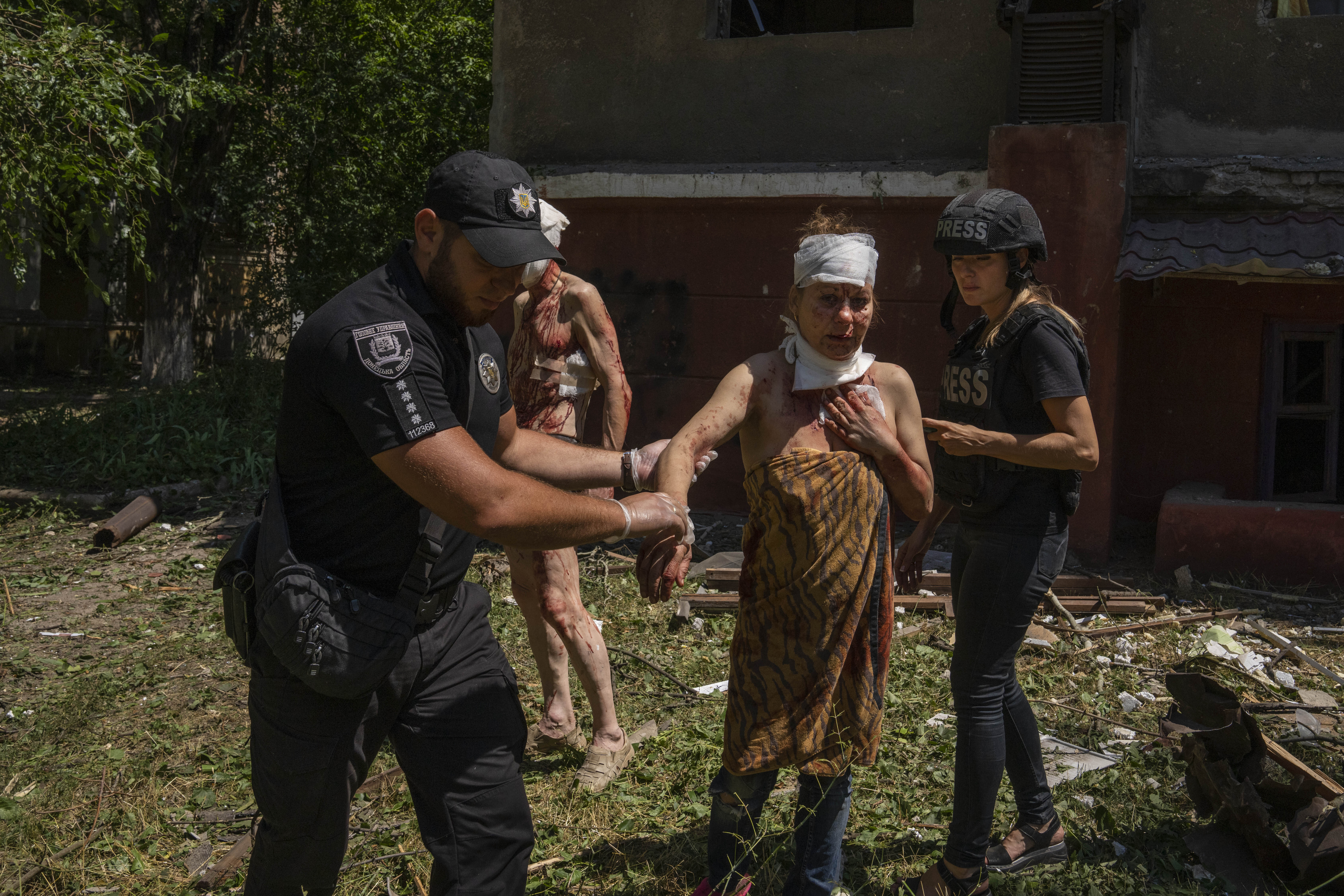 A policeman helps an injured woman after a missile strike hit a residential area, in Kramatorsk