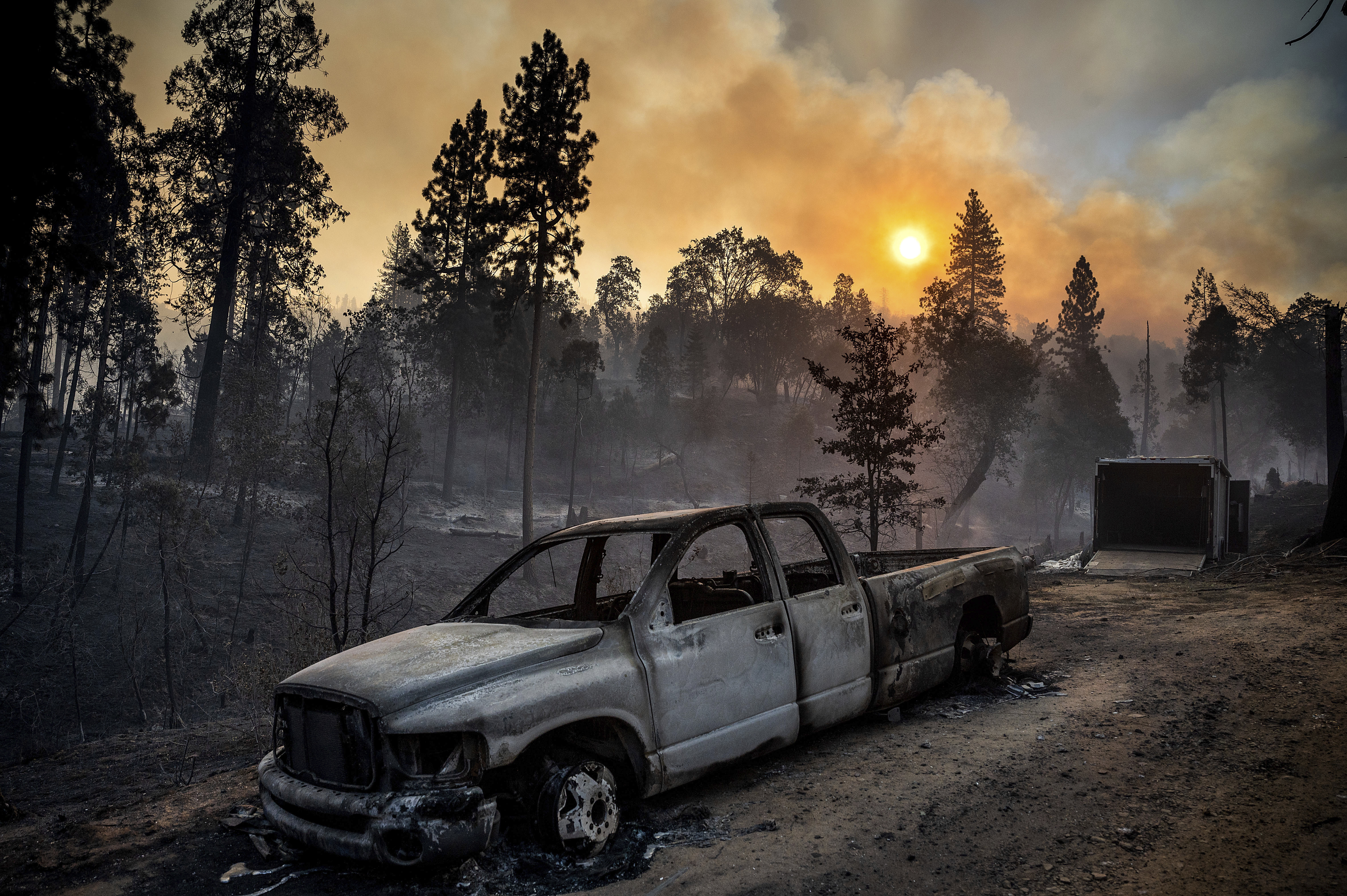 The Oak Fire burns behind a scorched pickup truck in the Jerseydale community