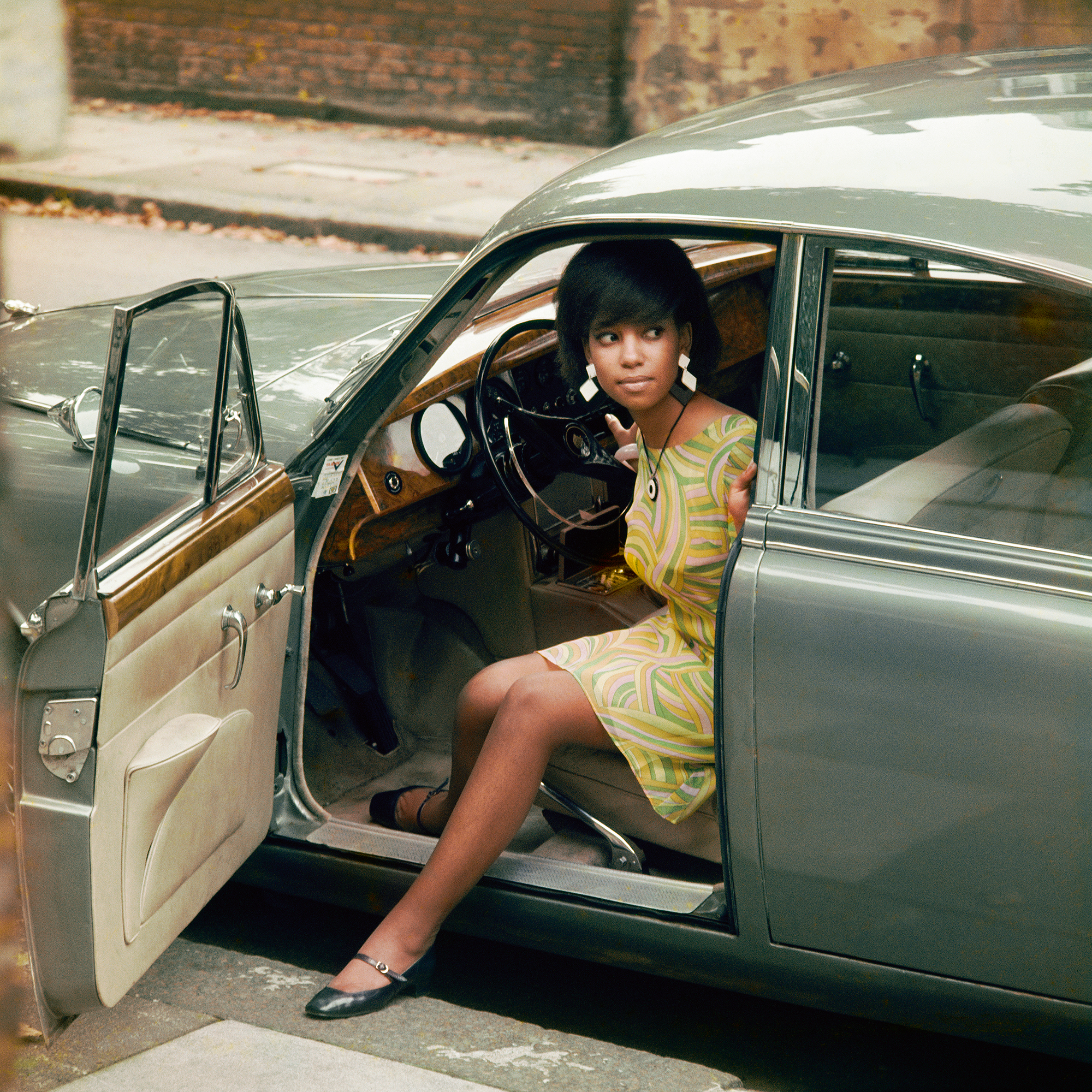 A woman steps out of a green Jaguar