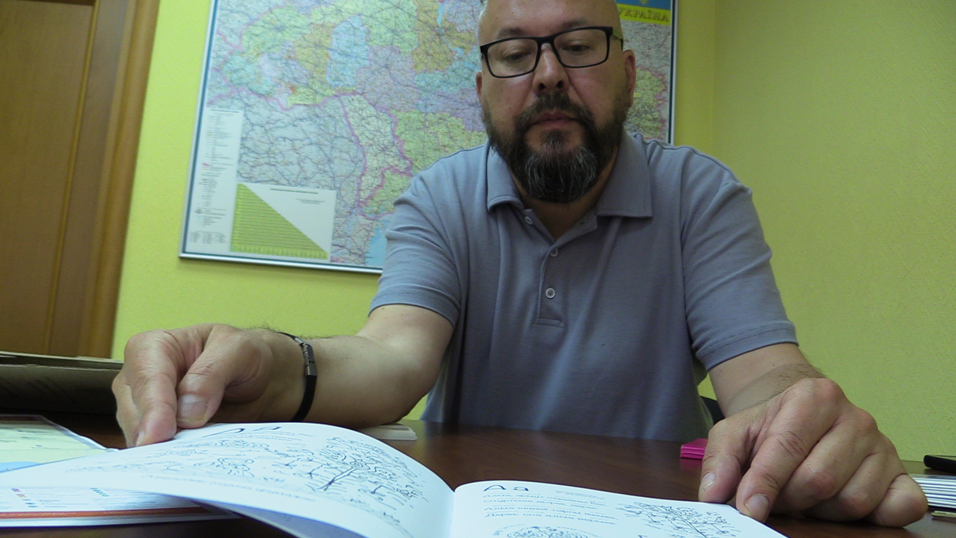 Linguist Oleksandr Rybalko shows a book in a Greek dialect spoken in Ukraine [Mansur Mirovalev/Al Jazeera]