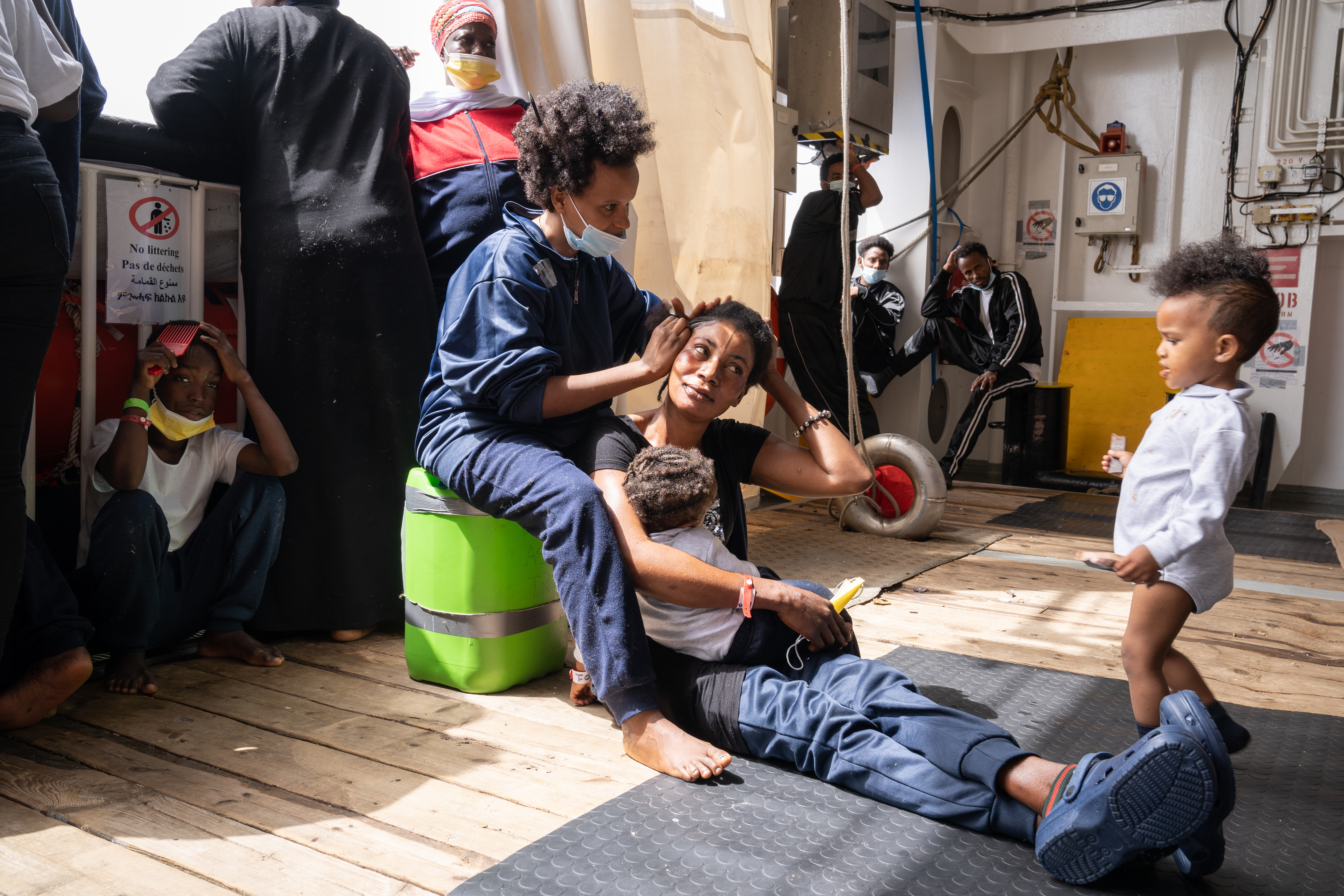 during visiting hours (when women can visit), while a fellow survivor tends to her hair. 