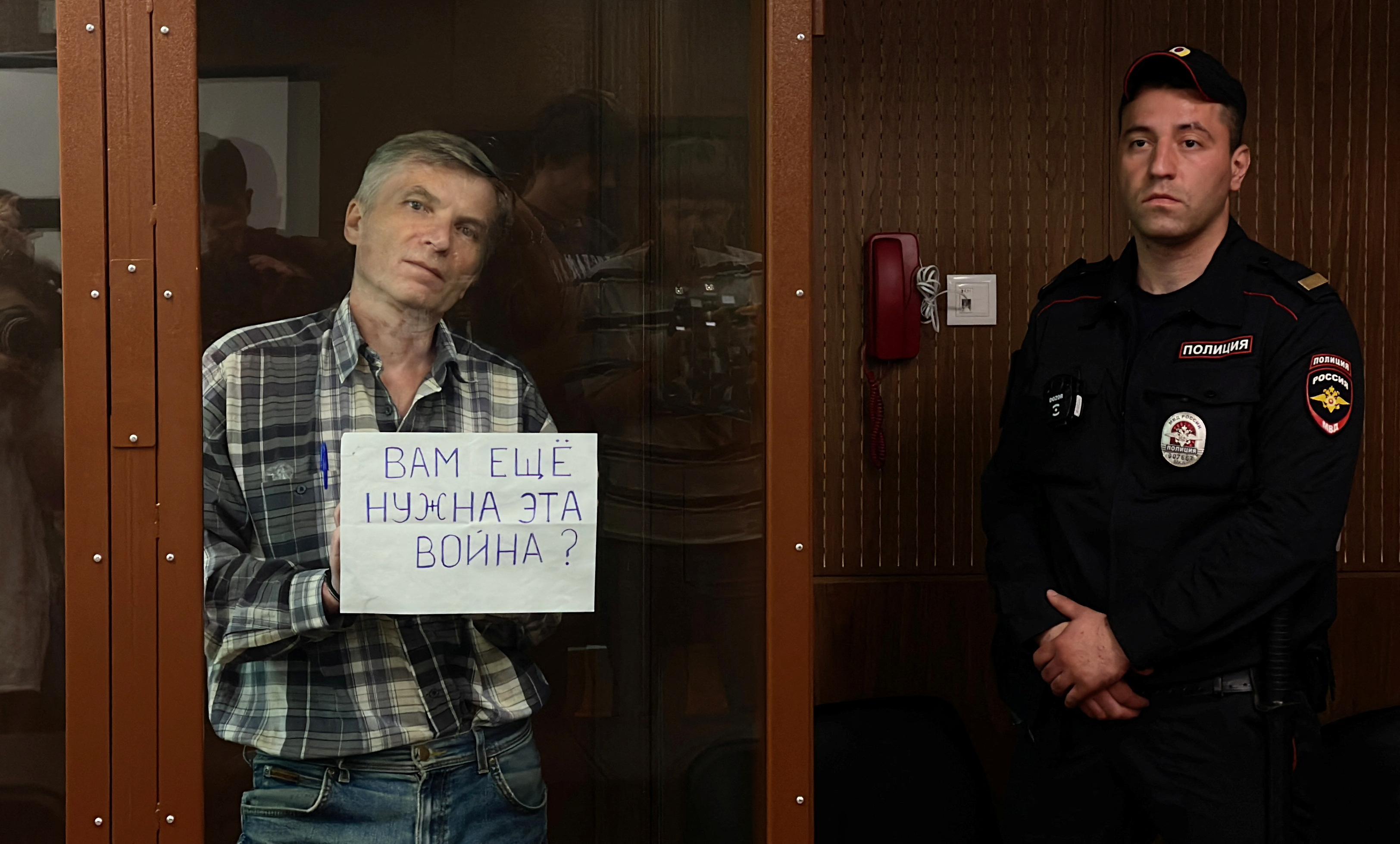 Moscow city councillor Alexei Gorinov, accused of "disseminating clearly false information about Russia's army", holds a placard reading "Do you still need this war?" as he stands inside a defendants' cage during a court hearing in Moscow, Russia
