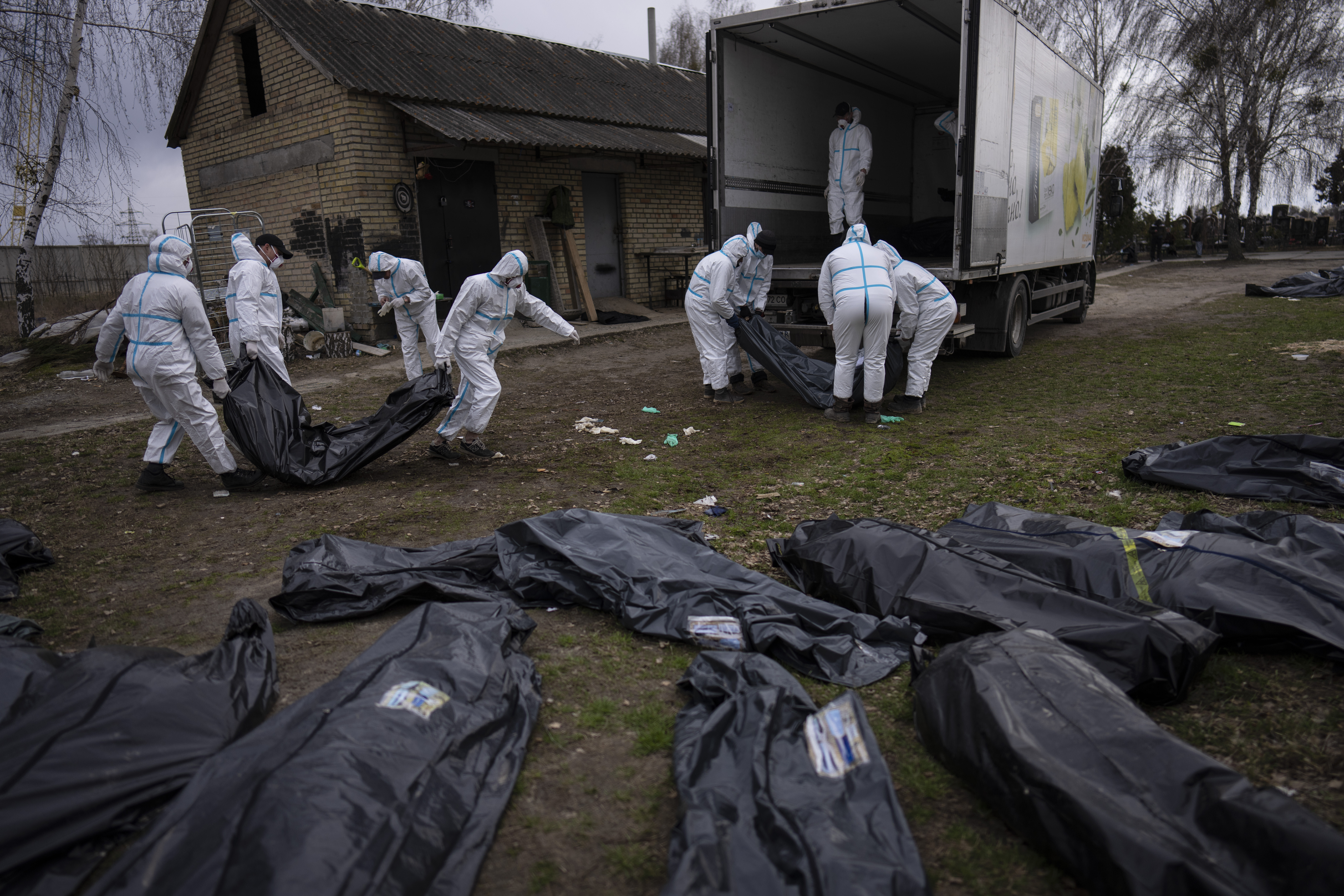 Volunteers load bodies of civilians killed in Bucha onto a truck to be taken to a morgue for investigation, in the outskirts of Kyiv, Ukraine, Tuesday, April 12