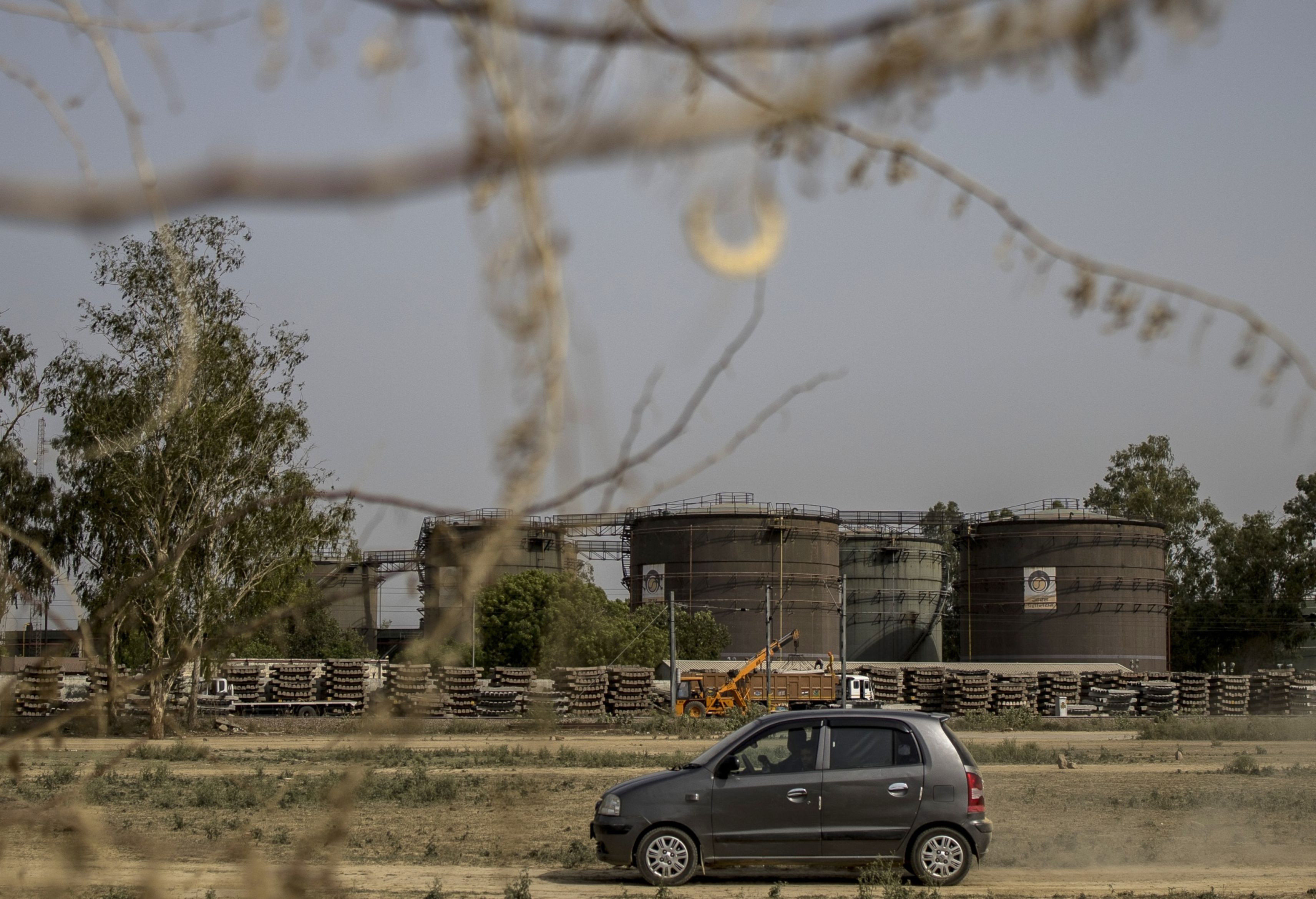 A car passes by an oil depot in New Delhi, India