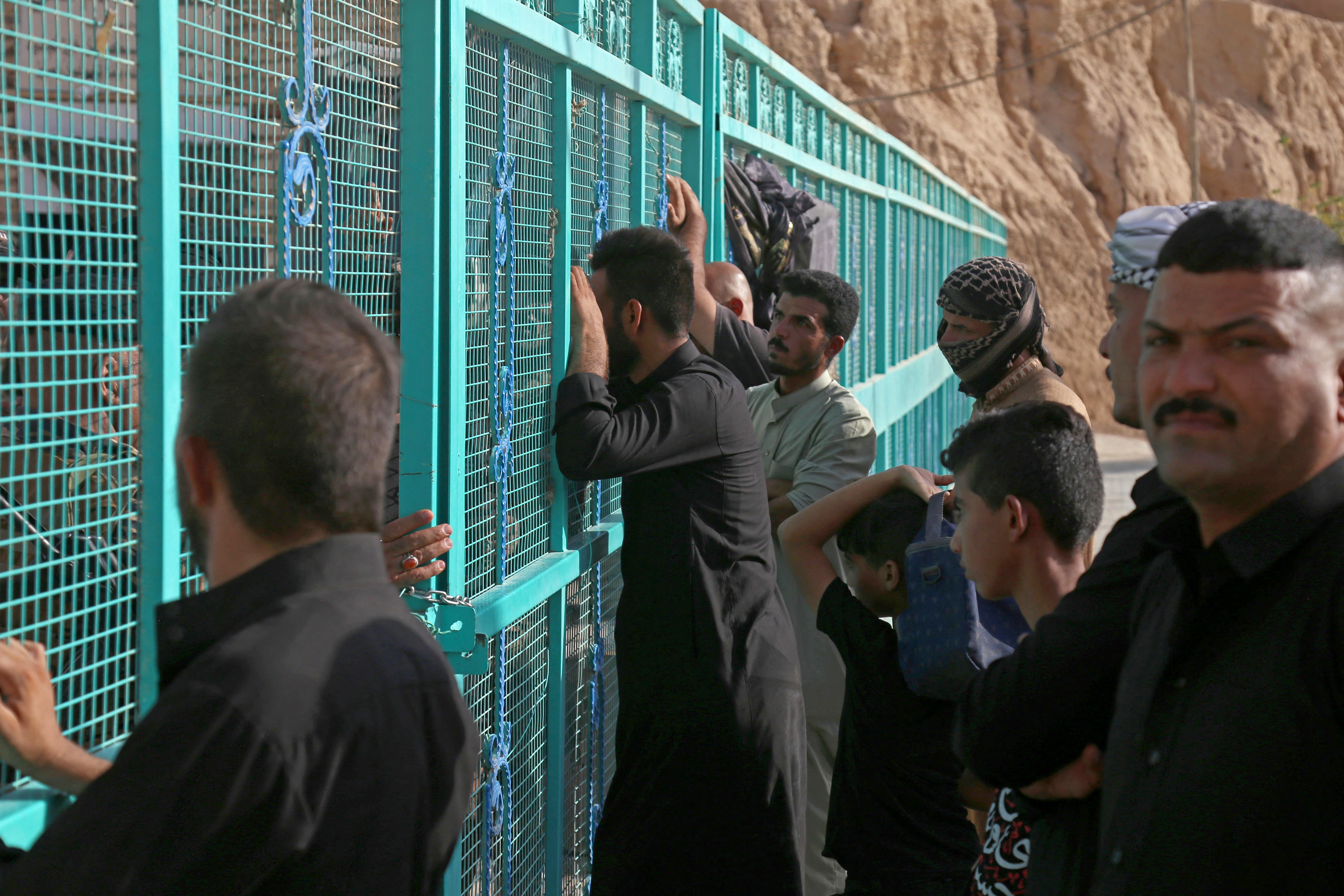 People wait as Iraqi rescue workers search for survivors after shrine collapse