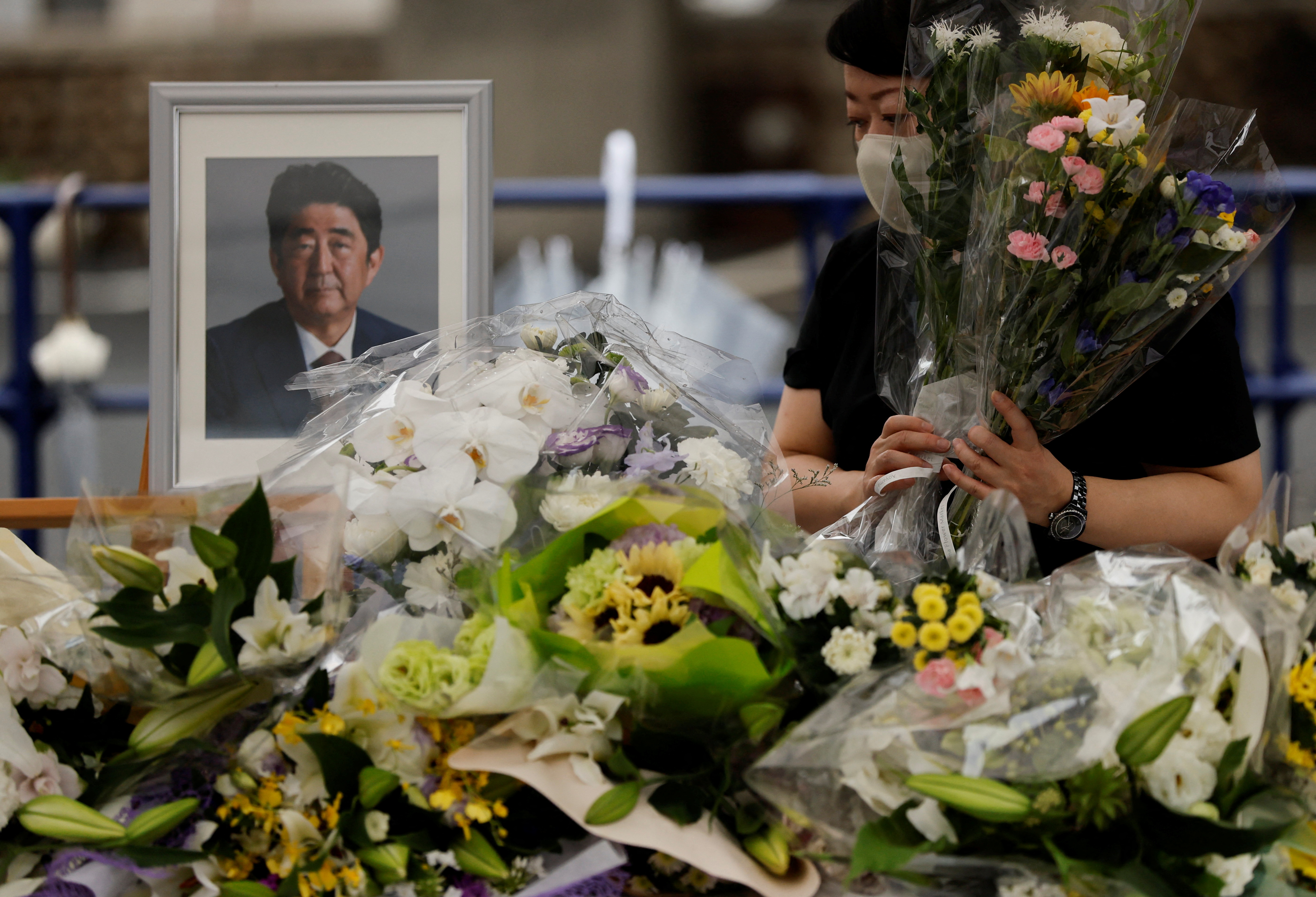 A mourner offers flowers next to a picture of late former Japanese Prime Minister Shinzo Abe