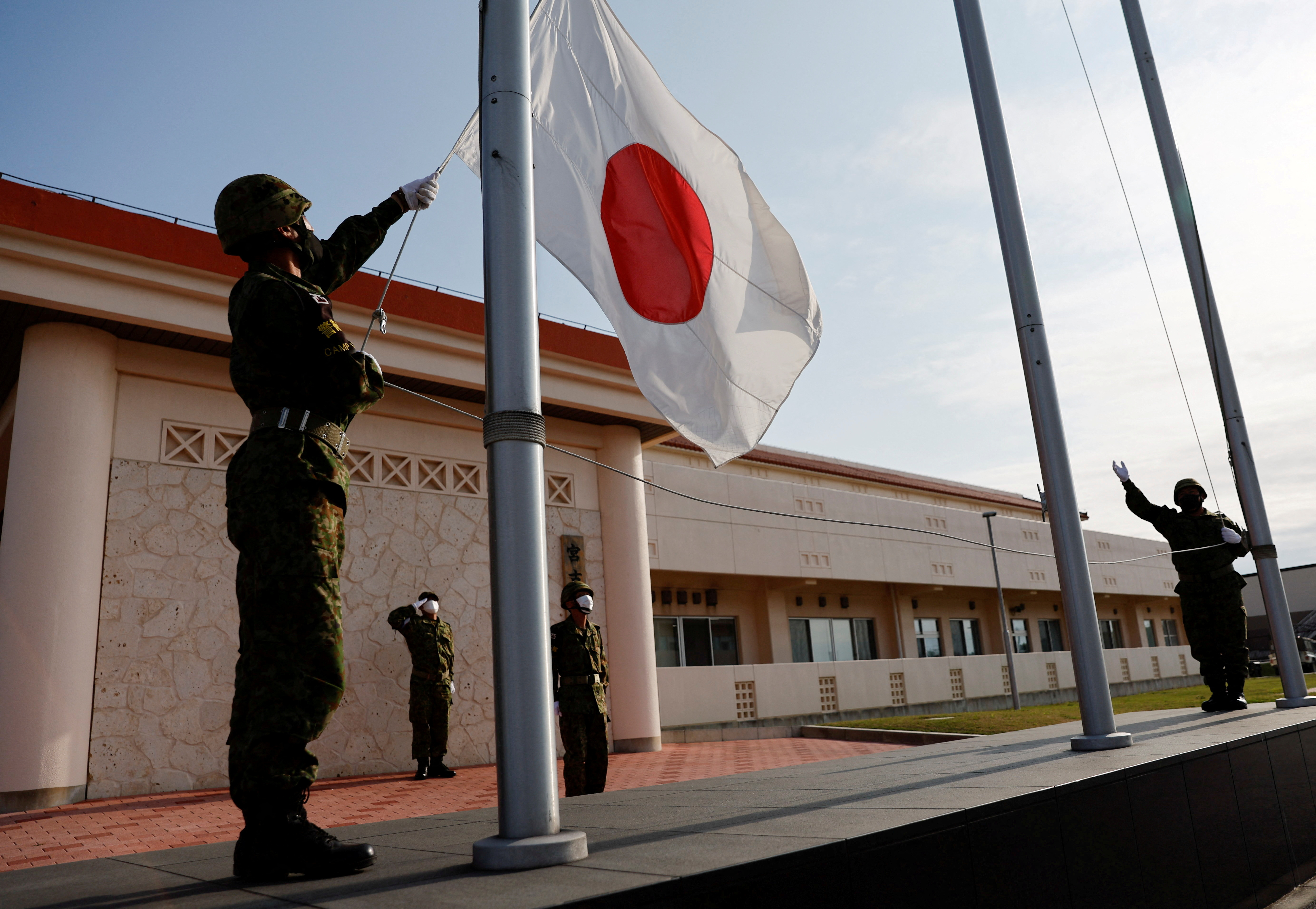 Members of the Japan Ground Self-Defense Force (JGSDF) lower the Japanese national flag in the early evening