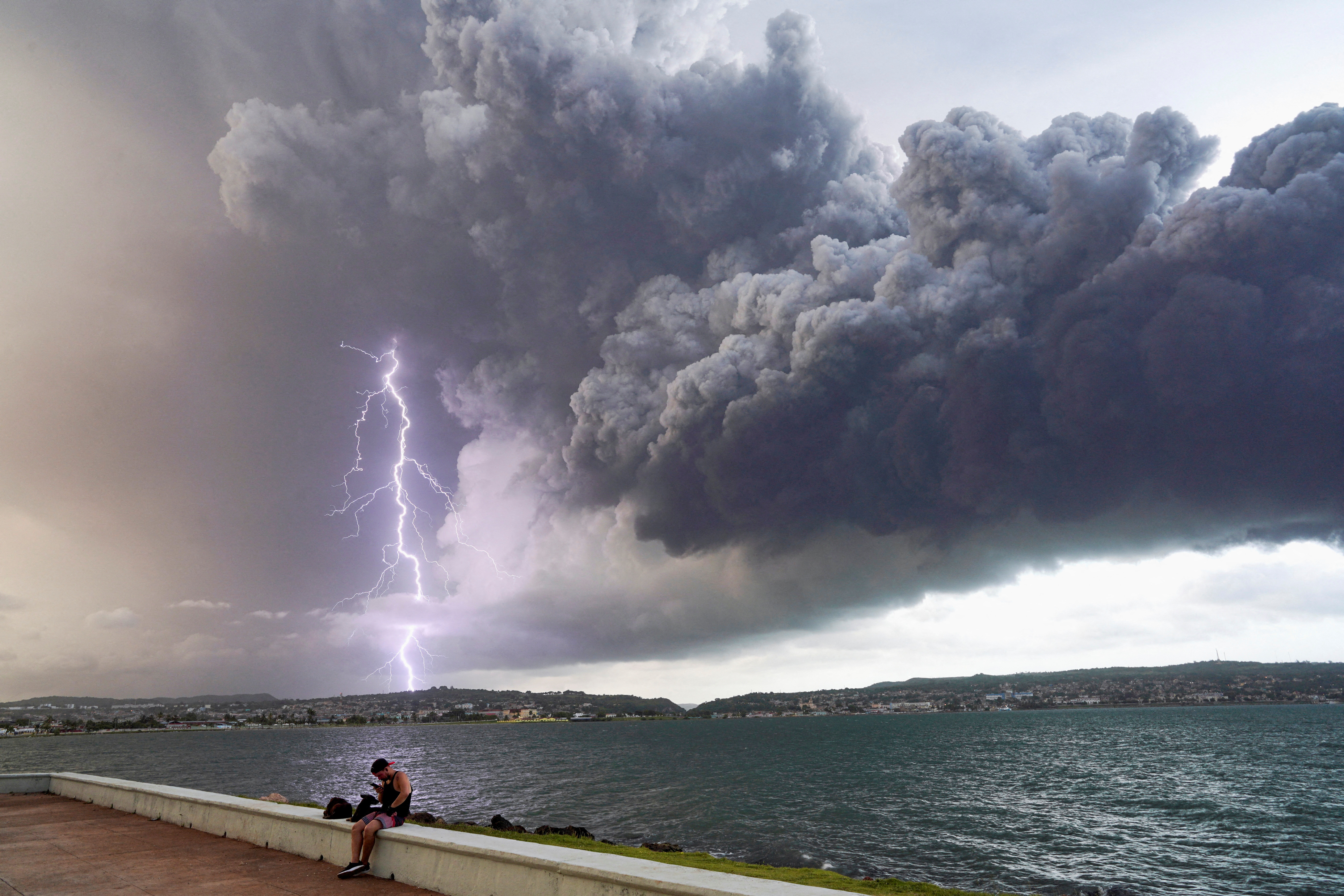 A lightning strikes through smoke from fuel storage tanks that exploded near Cuba's supertanker port in Matanzas, Cuba,