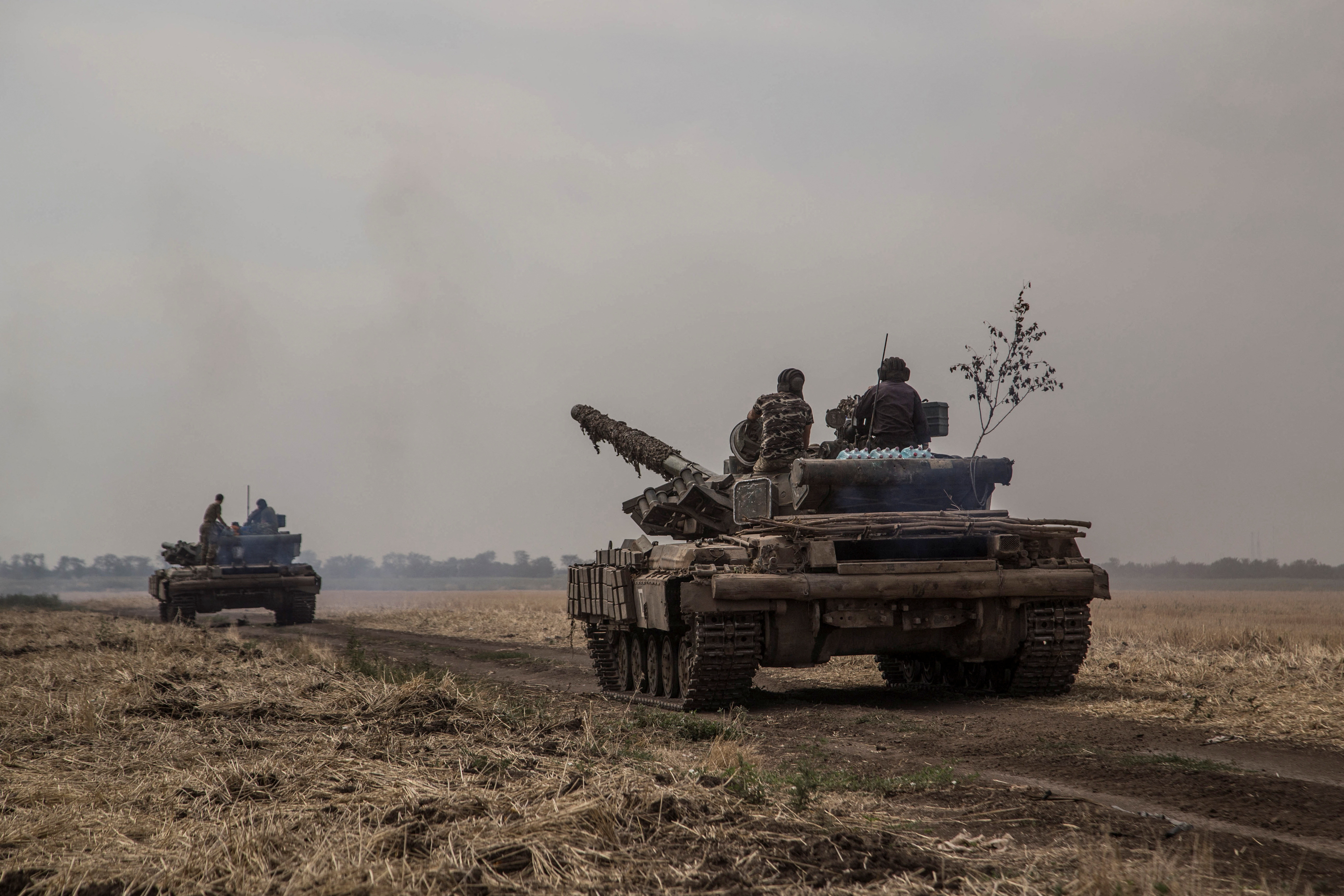 Ukrainian servicemen ride atop tanks near a front line in Mykolaiv