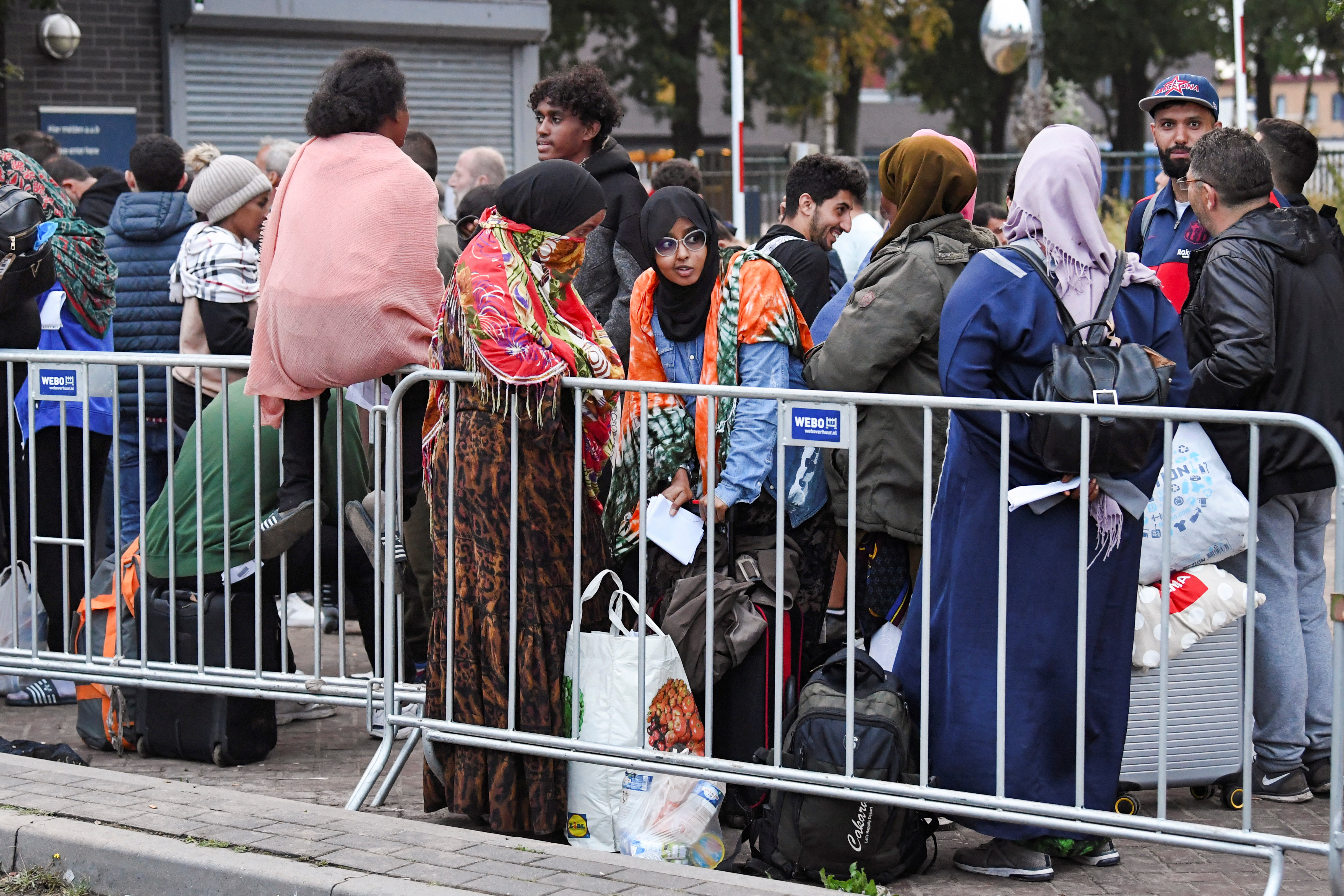 Refugees wait outdoors on the damp ground at the main reception centre for asylum seekers, in Ter Apel, Netherlands August 17, 2022. More than a hundred people have spent nights outdoors, sleeping on the roadside with little or no access to shelter or food. REUTERS/Piroschka van de Wouw