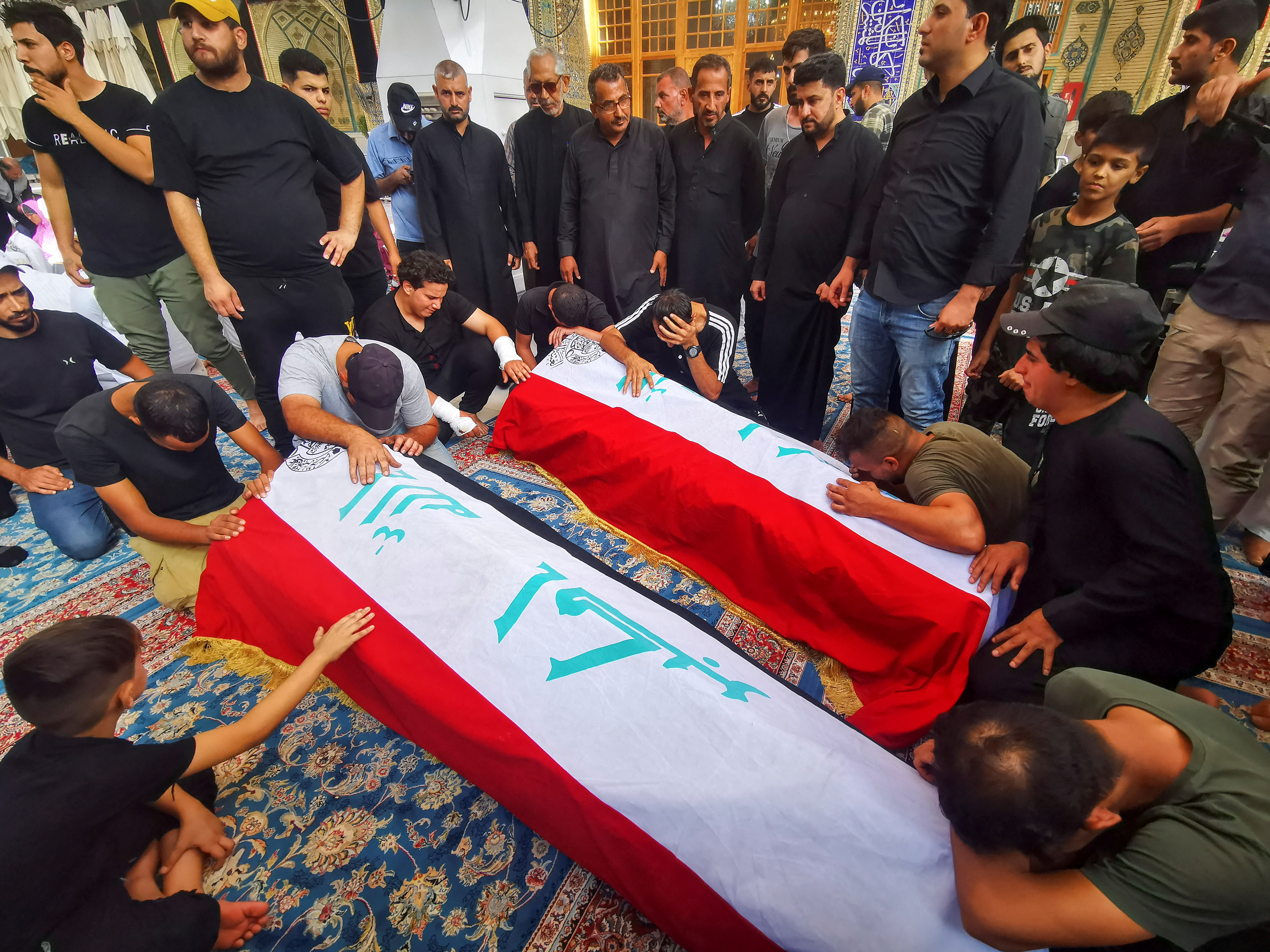 Mourners pray in front of the coffins of supporters of Iraqi populist leader Moqtada al-Sadr, who were killed during clashes in Baghdad, during their funeral in Najaf, Iraq August 30, 2022