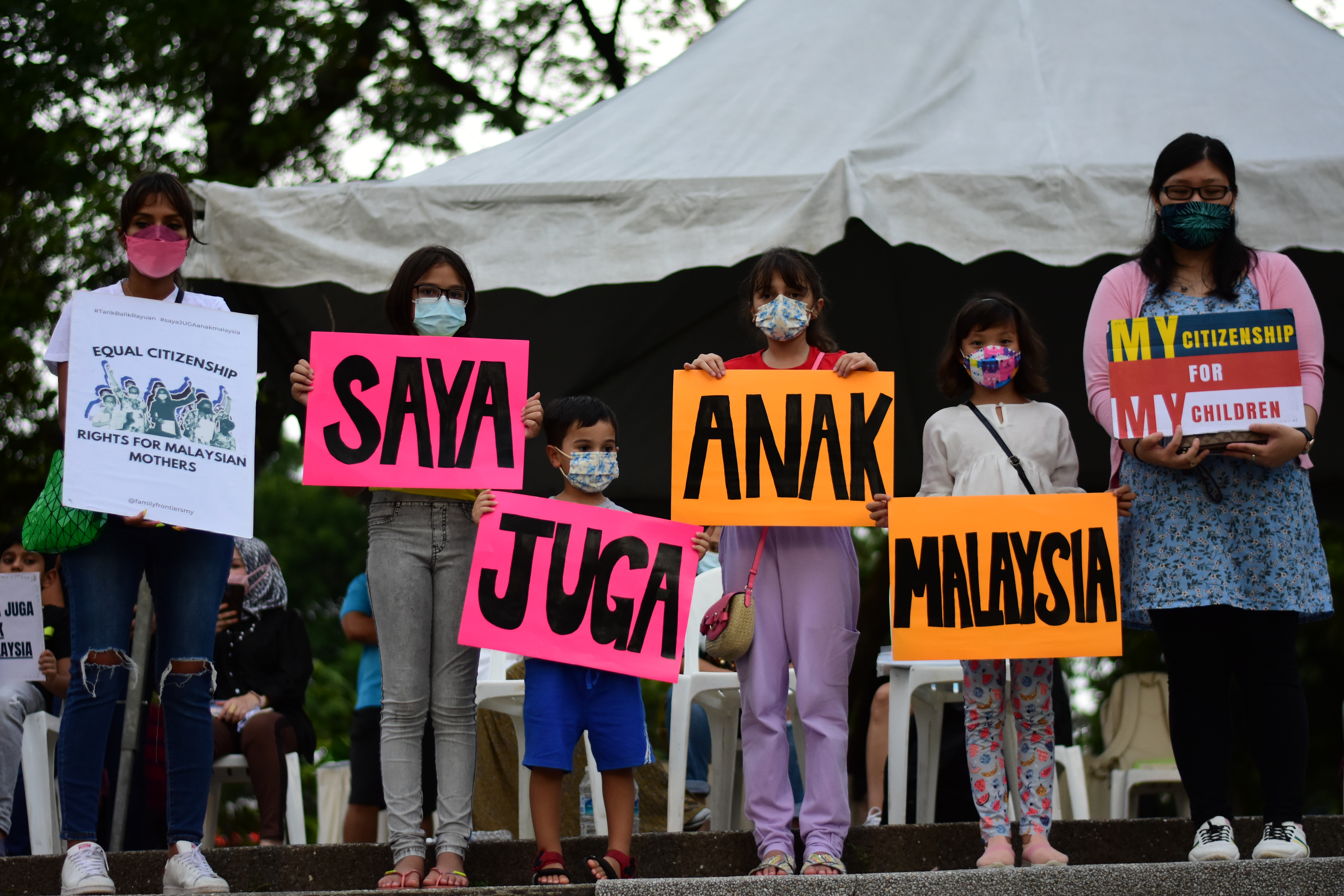 Six children born overseas to Malaysian mothers campaign for equal citizenship rights holding banners that spell out Saya Juga Anak Malaysia (I'm also a child of Malaysia).