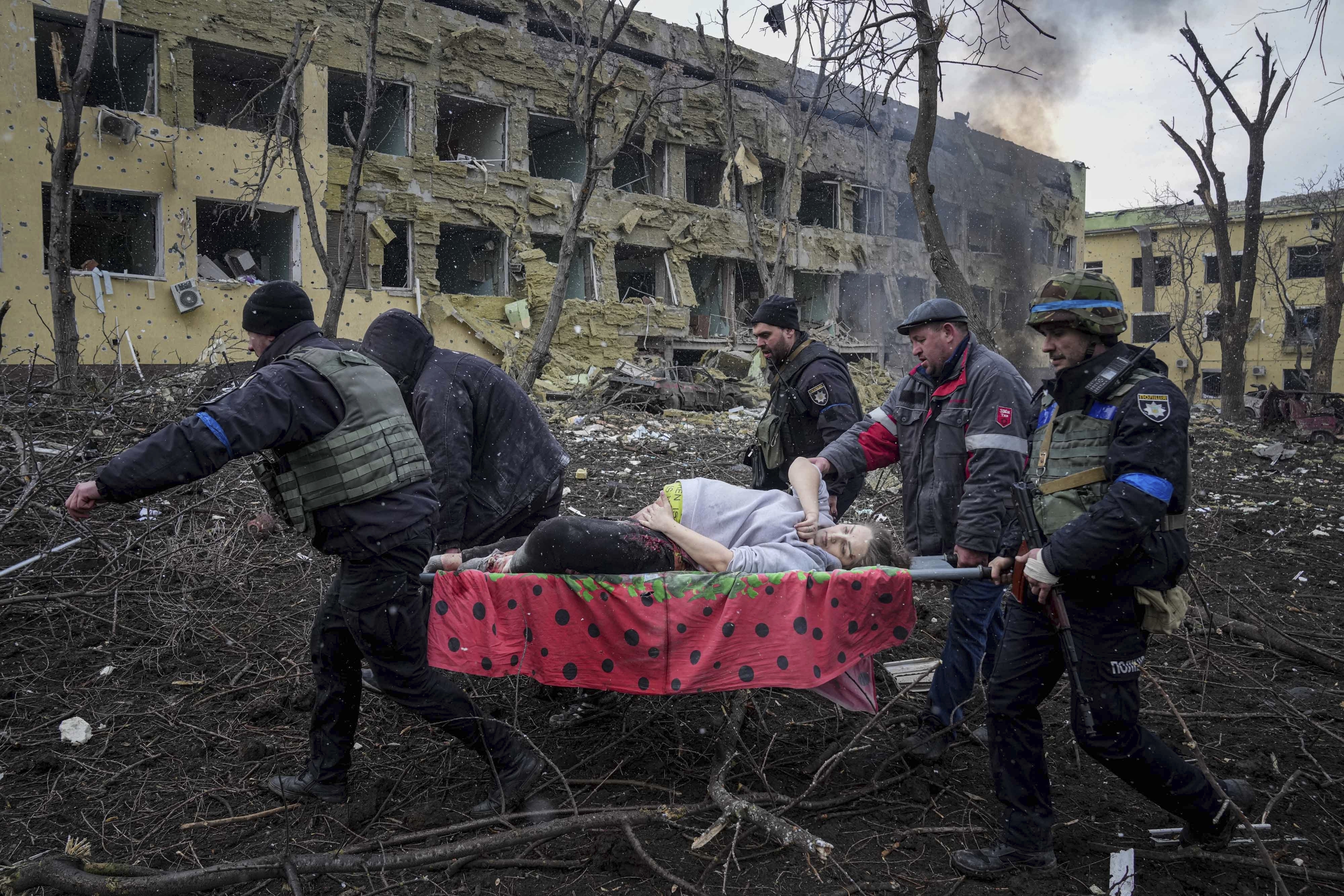 Ukrainian emergency employees and volunteers carry an injured pregnant woman from the maternity hospital that was damaged by shelling in Mariupol, Ukraine