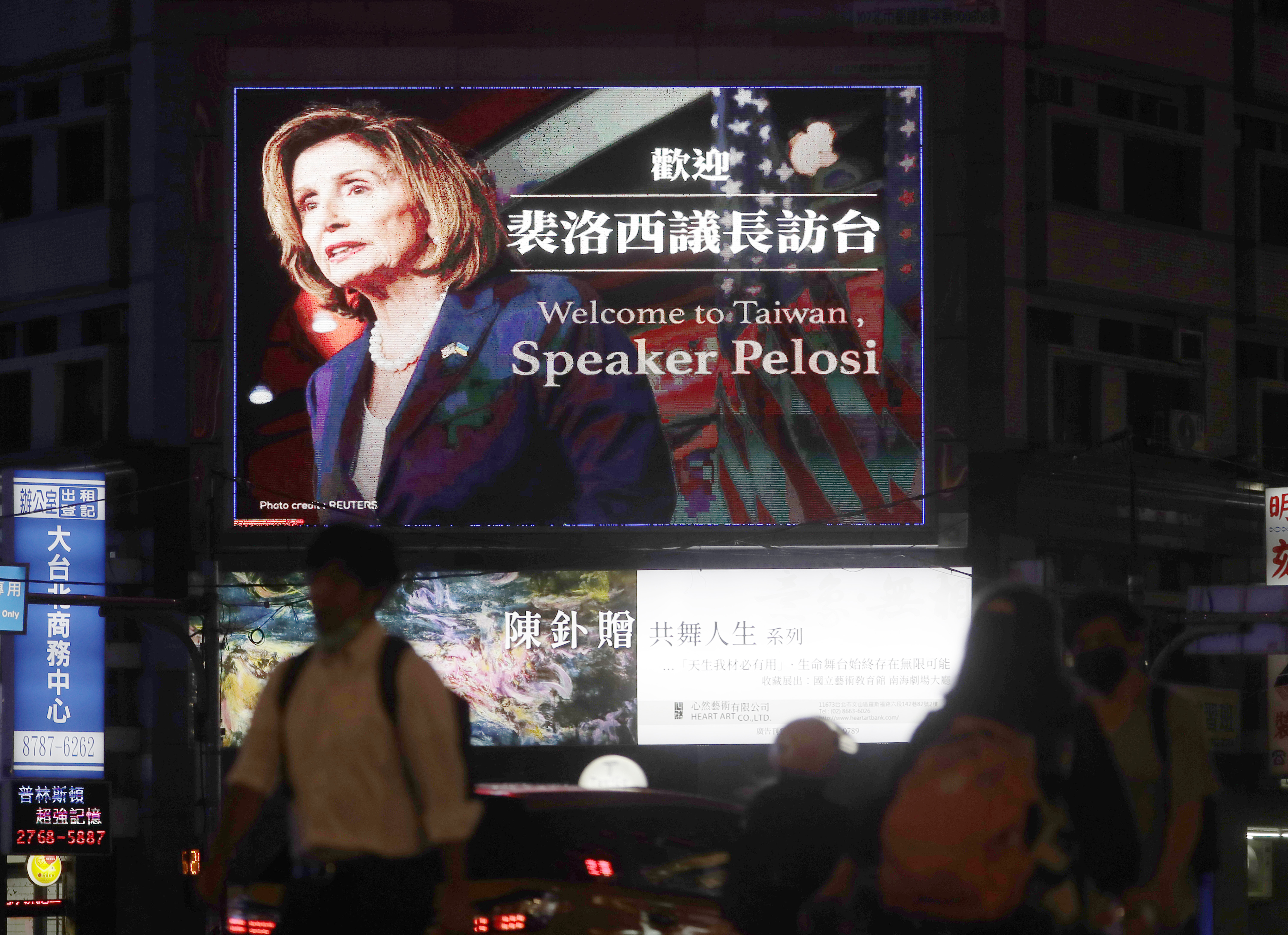 People walk past a billboard welcoming US House Speaker Nancy Pelosi, in Taipei, Taiwan.