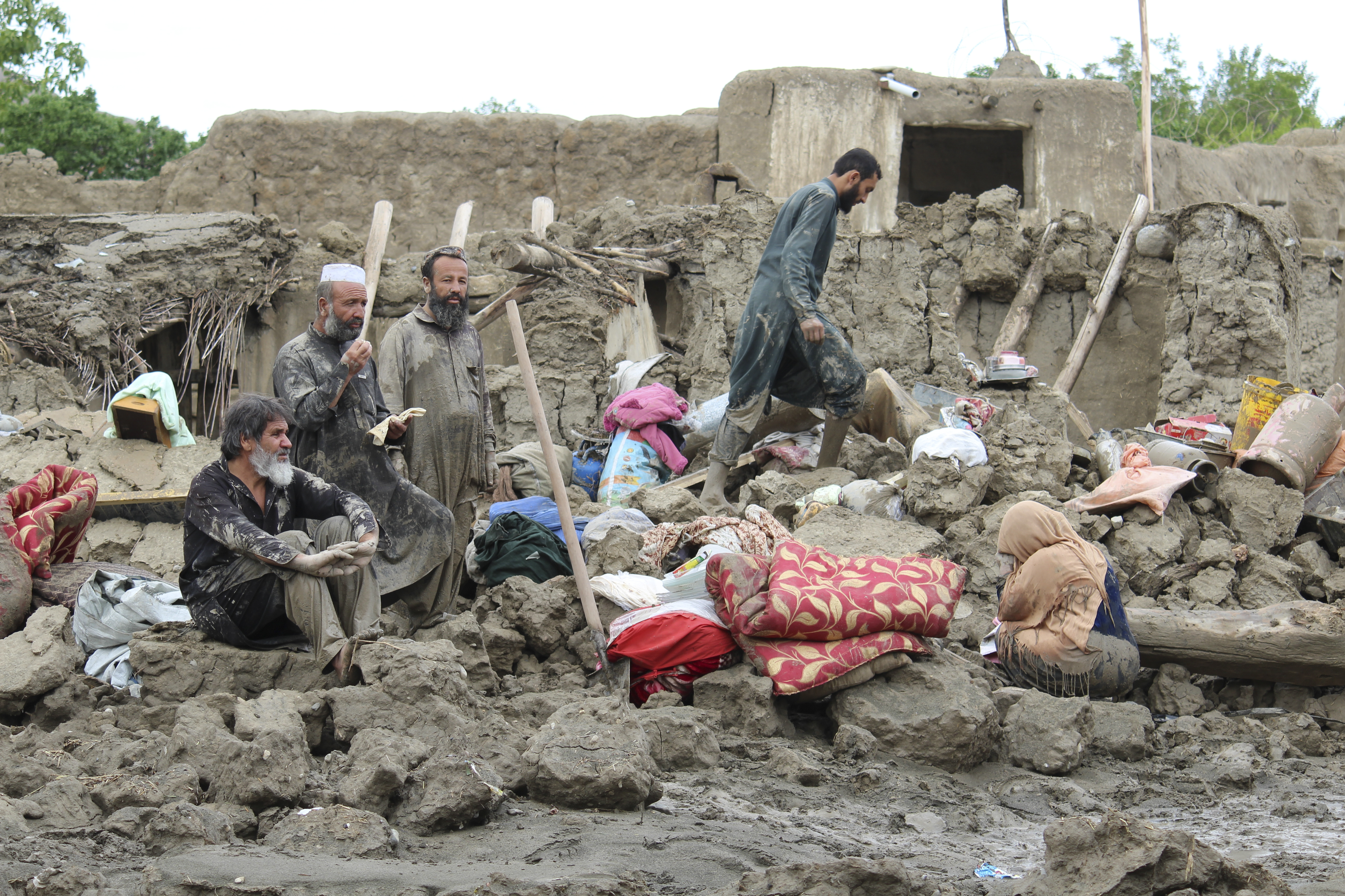 People collect their belongings from their damaged homes after heavy flooding in the Khushi district of Logar province