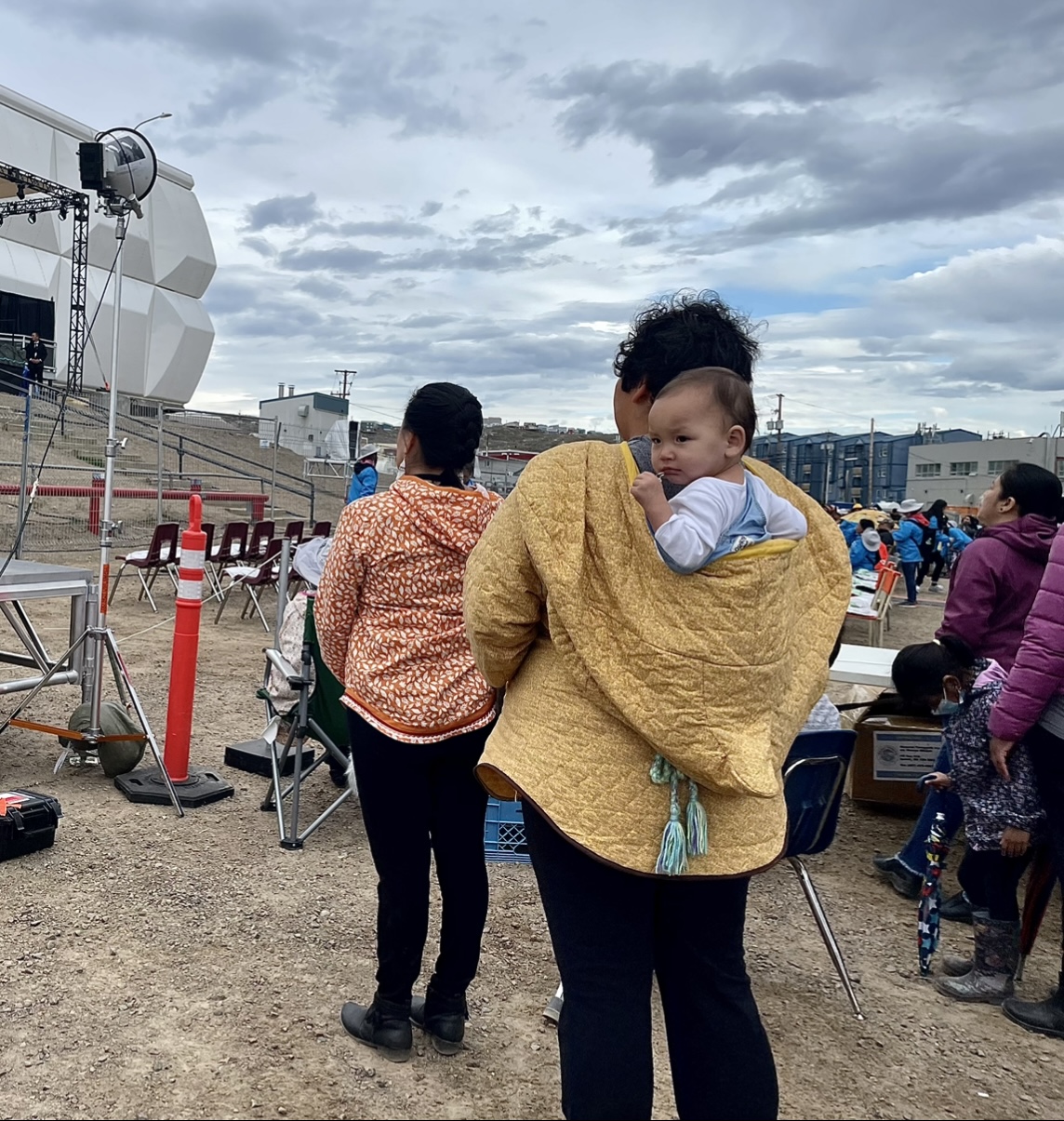 A photo of a person holding a baby on their back.