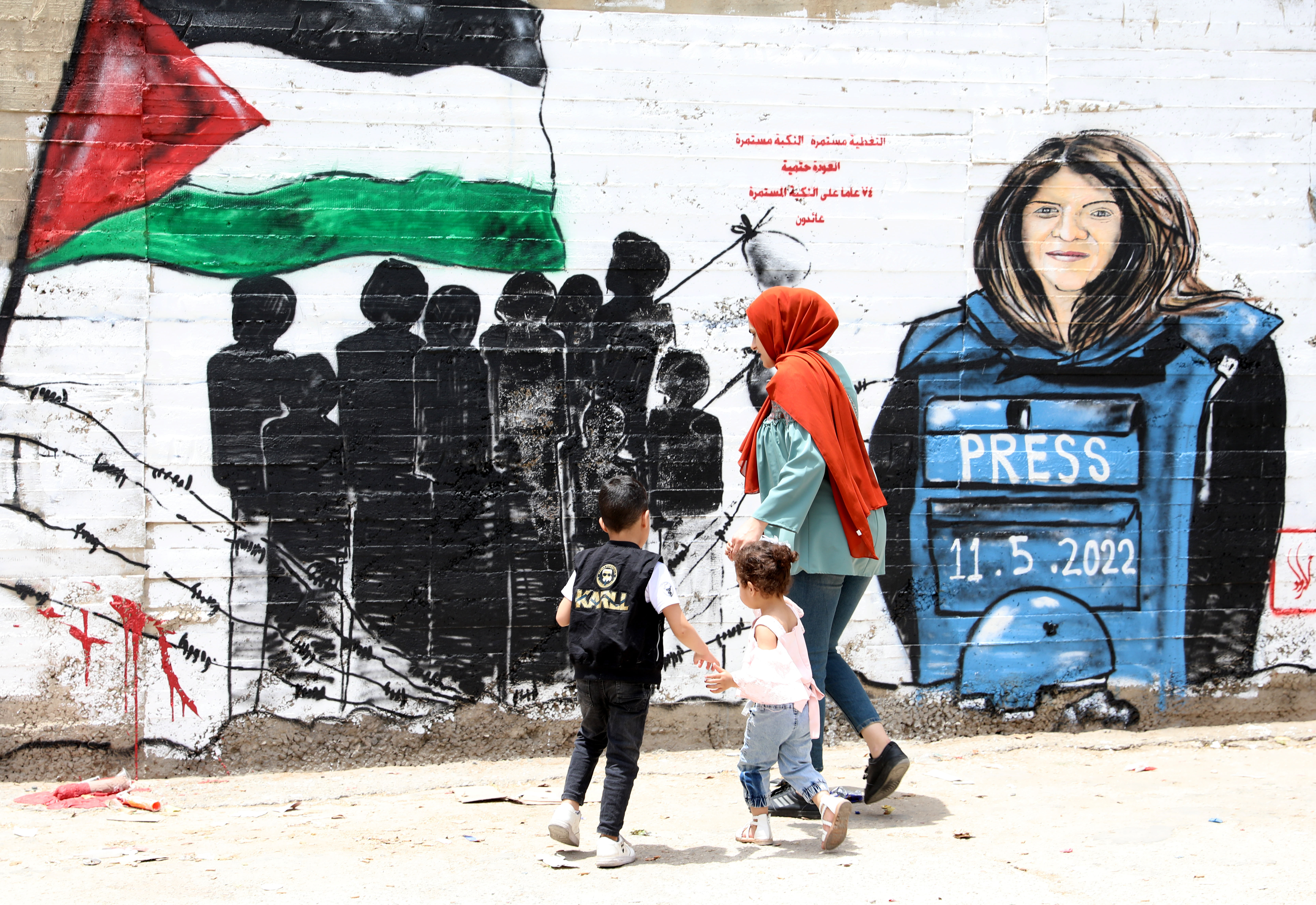 Palestinians walk in front of a mural for Al Jazeera journalist Shireen Abu Akleh in the occupied West Bank city of Bethlehem.
