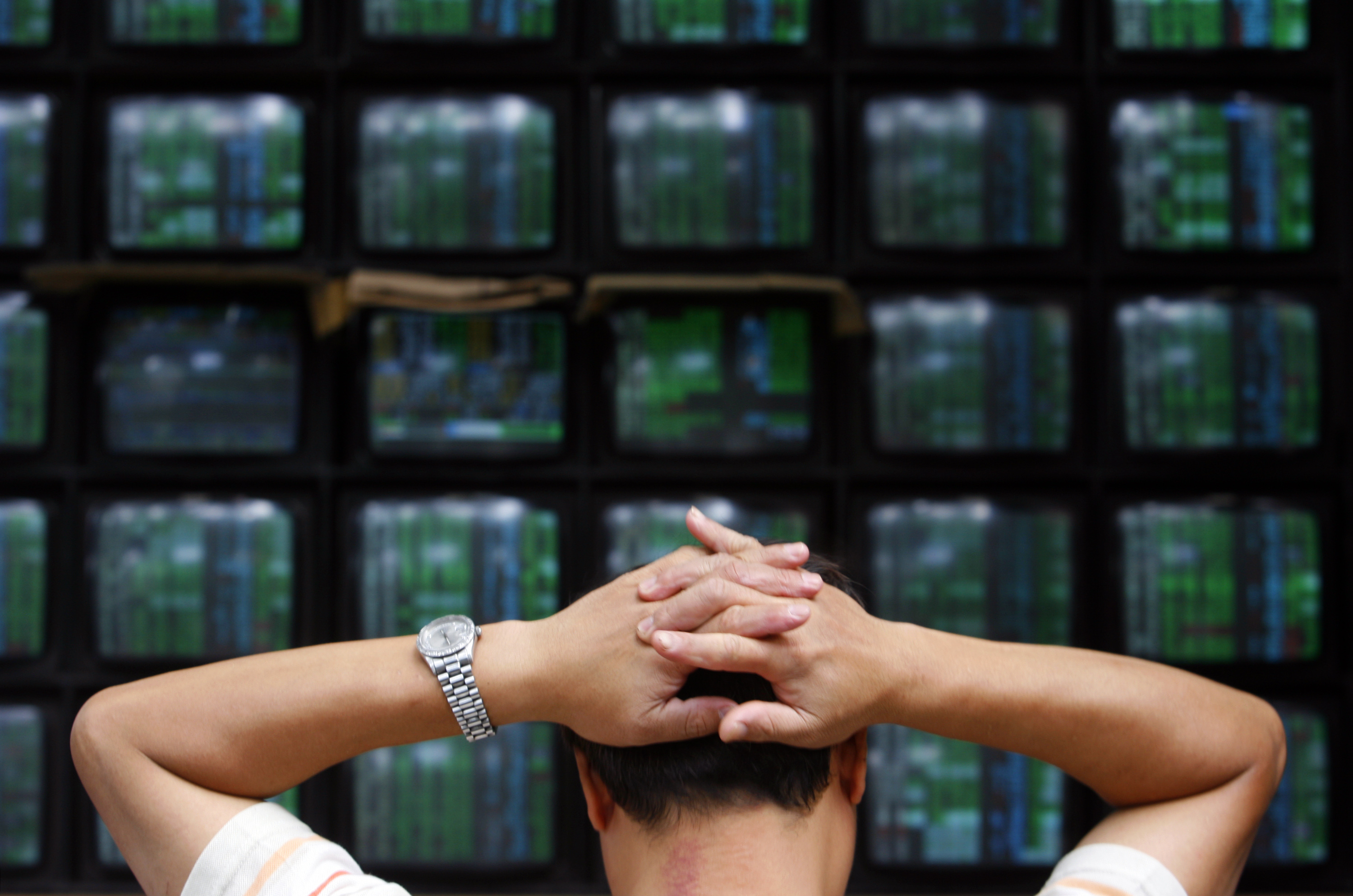 A man looks at stock market monitors in Taipei